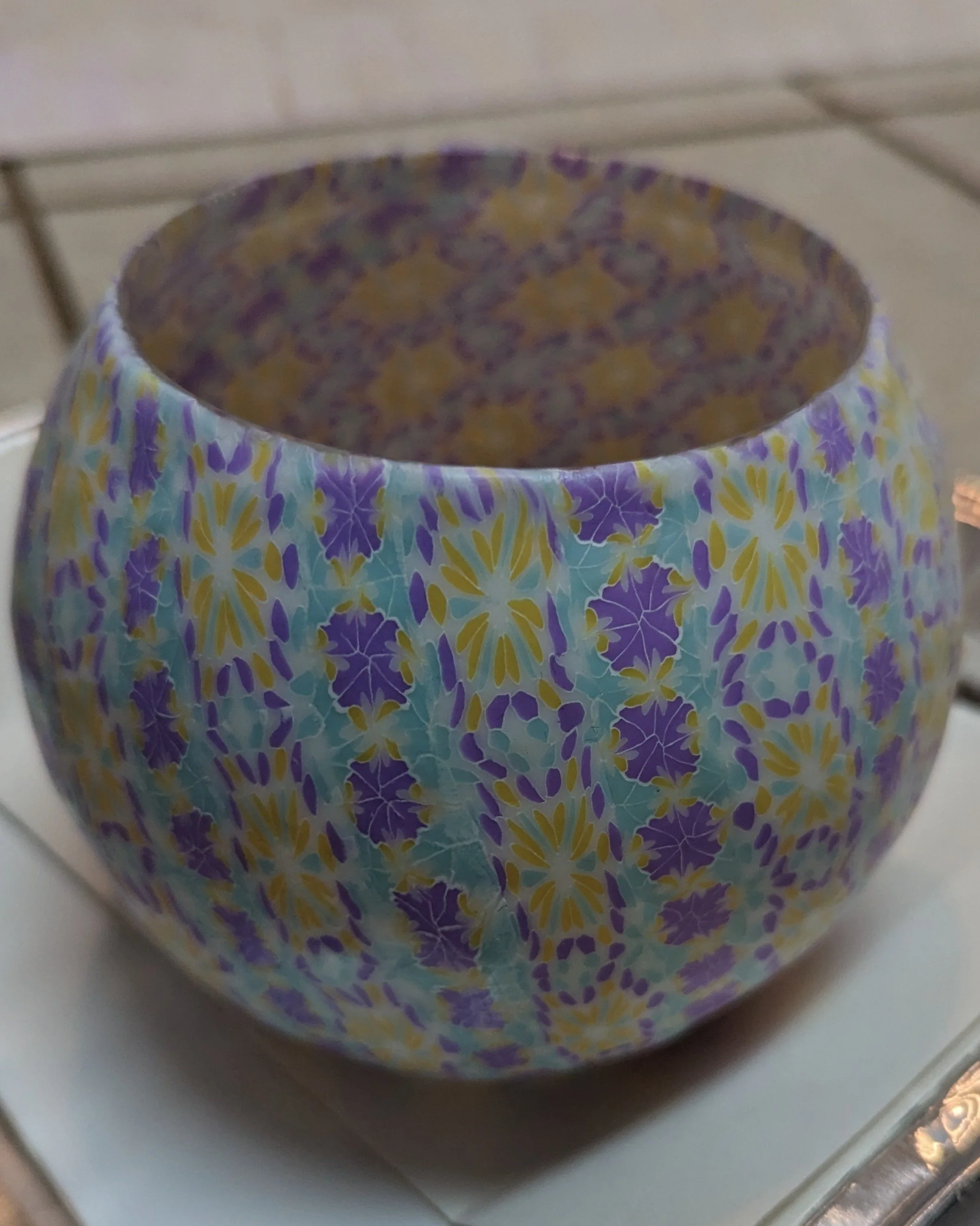 Close up profile of the Translucent Floral Candle Holder by Art Illusions by Young. The thickness of the hand-layered translucent polymer clay over glass is visible, with floral motifs and swirling patterns in soft Carnival colors creating depth and 