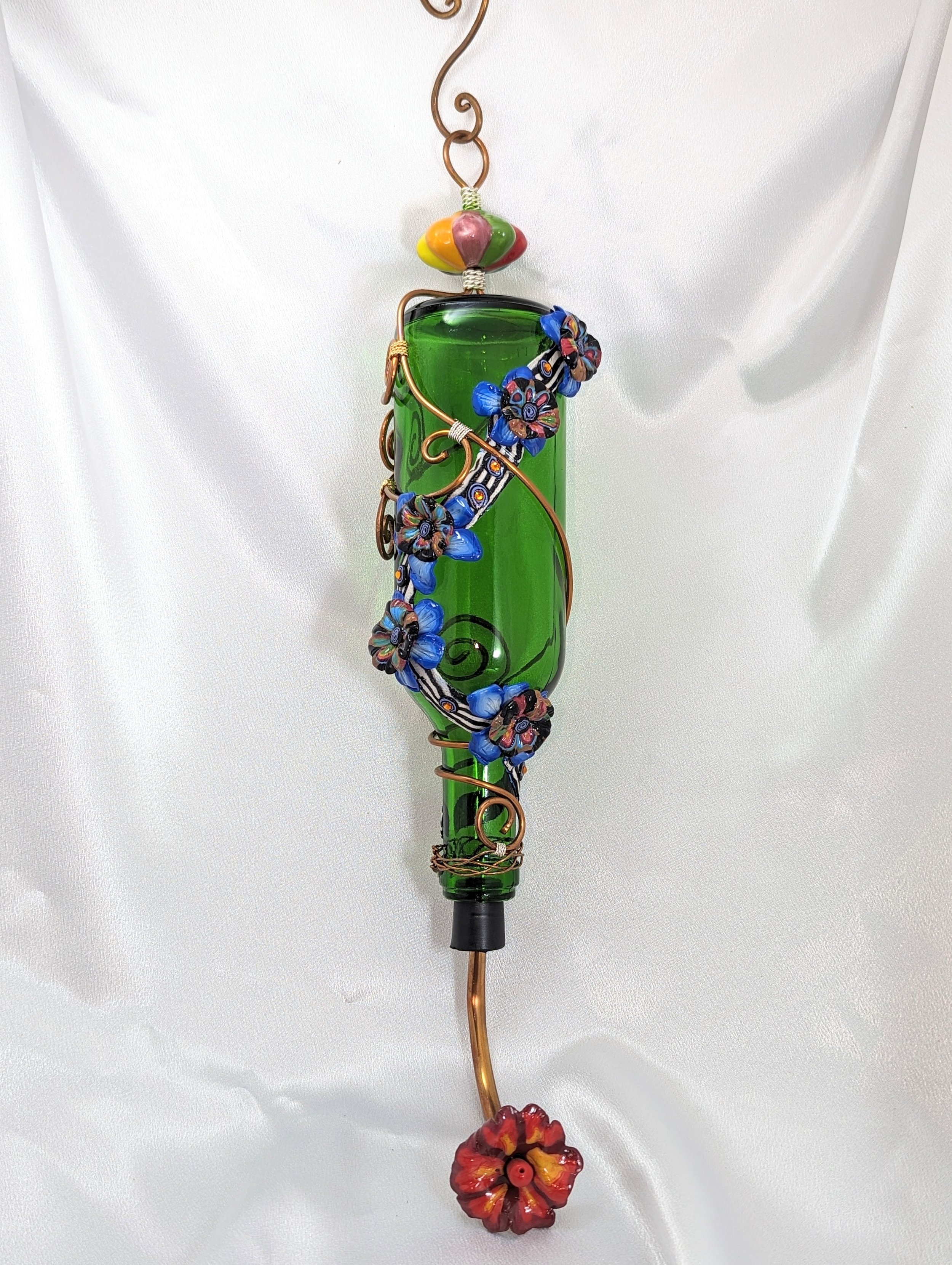Green glass hummingbird feeder by Art Illusions by Young featuring colorful copper wire wrapping, flowers, and decorative elements.
