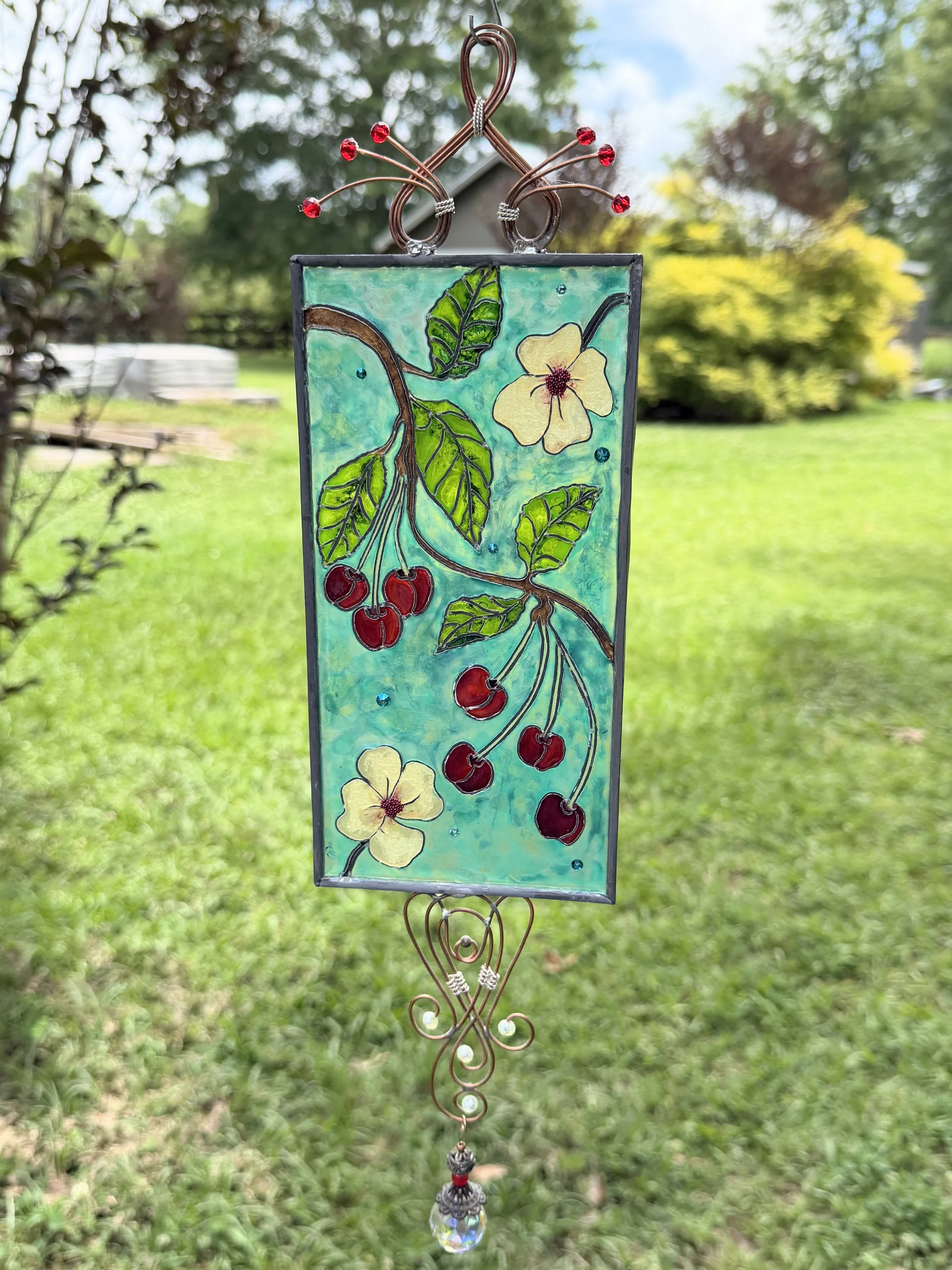 Cherry Jubilee by Art Illusions by Young. A joyful celebration of summer’s bounty bursts with life in this hand-painted and leaded Illusion Glass panel. Clusters of ripe, glossy red cherries hang from delicate branches alongside soft white blossoms a