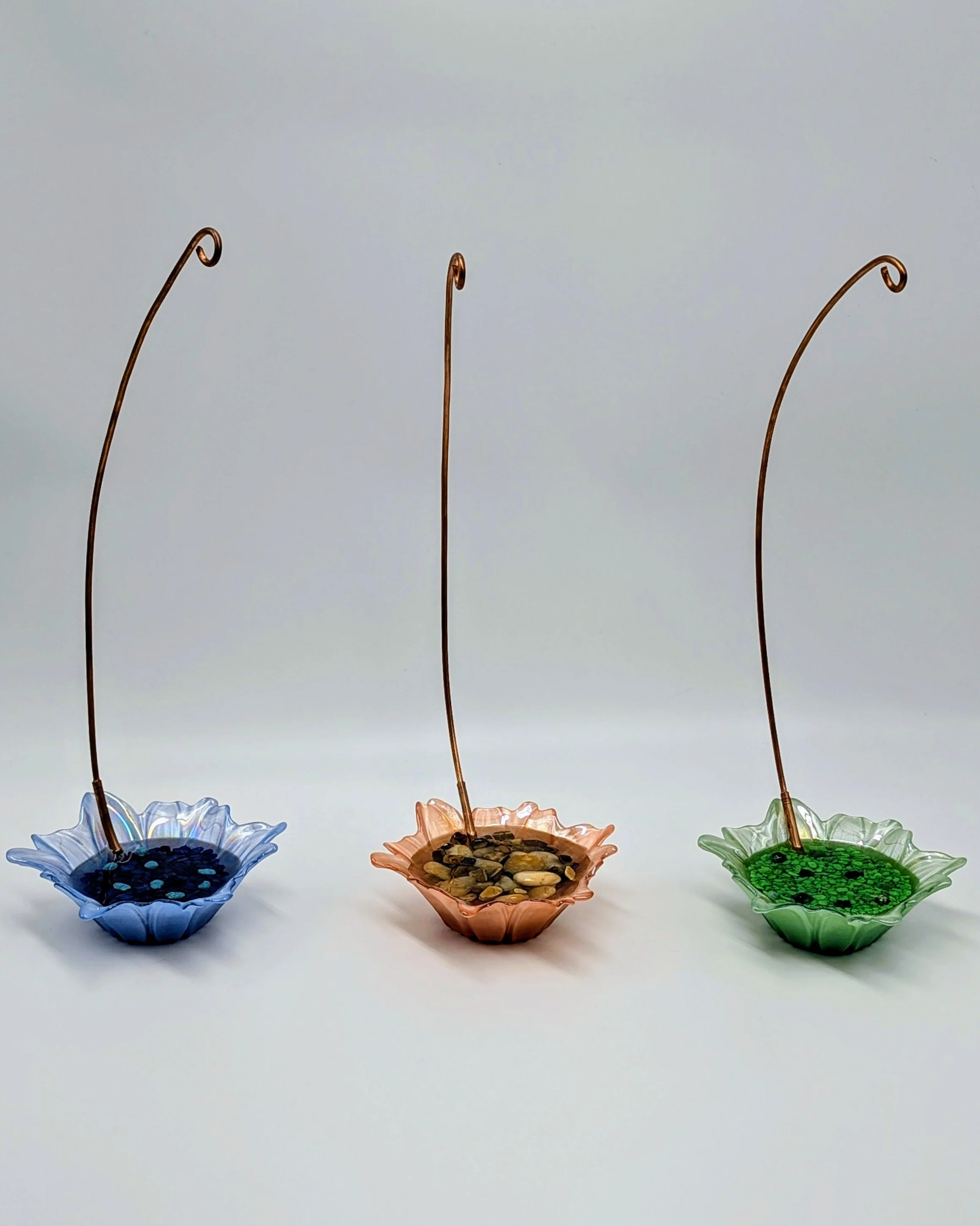 Set of Three Daisy-Style Colored Glass Display Stands
This charming trio of handcrafted display stands features delicate daisy-shaped glass bases in vibrant blue, warm peach, and fresh green. Each is paired with a tall, gracefully curved copper rod, 