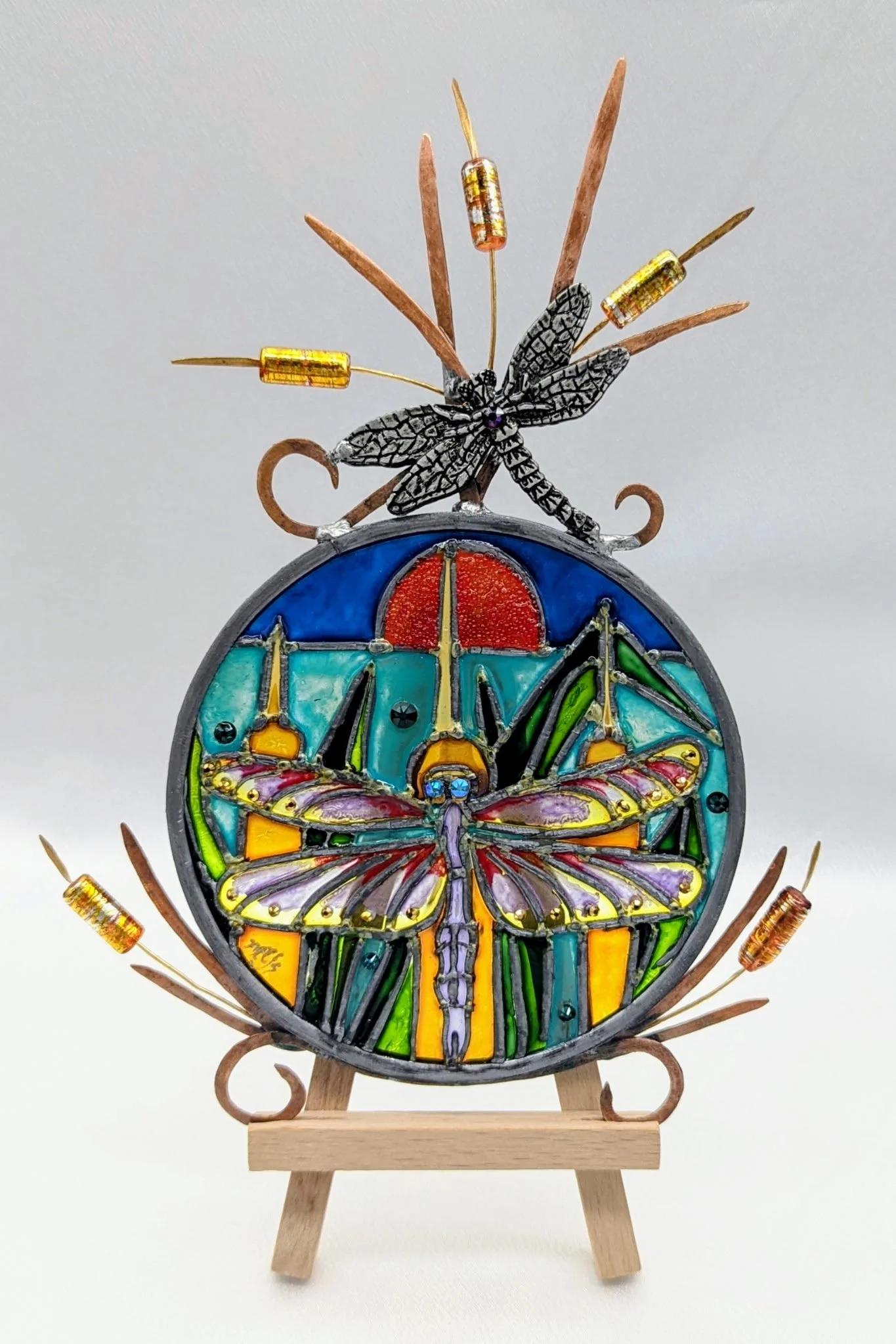 🔴 Sold: 
Mini Dragonfly Illusion Glass by Art Illusions by Young, Folsom, Louisiana. This delicate miniature suncatcher features a graceful dragonfly with iridescent wings hovering above stylized cattails and marsh grasses against a vibrant sunset s