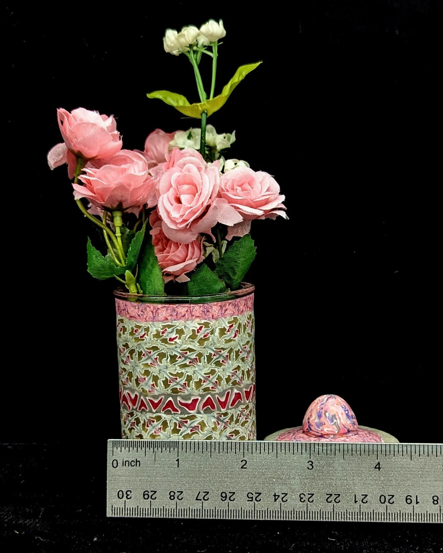 Close-up of the Floral Lace Trinket Jar by Art Illusions by Young with lid removed and pink flowers inside. The domed lid with sculpted knob sits beside the jar, revealing the horizontal measurements and displaying the rich lace-like patterns in soft