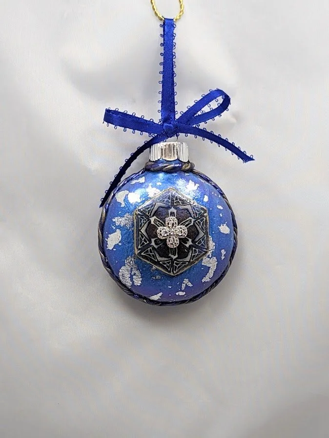 🔴 Sold: 
Blue Christmas Ornament by Art Illusions by Young, Folsom, Louisiana. This elegant spherical ornament features a deep blue background with intricate hand-sculpted details, accented with sparkling elements. Handcrafted in polymer clay, it ca