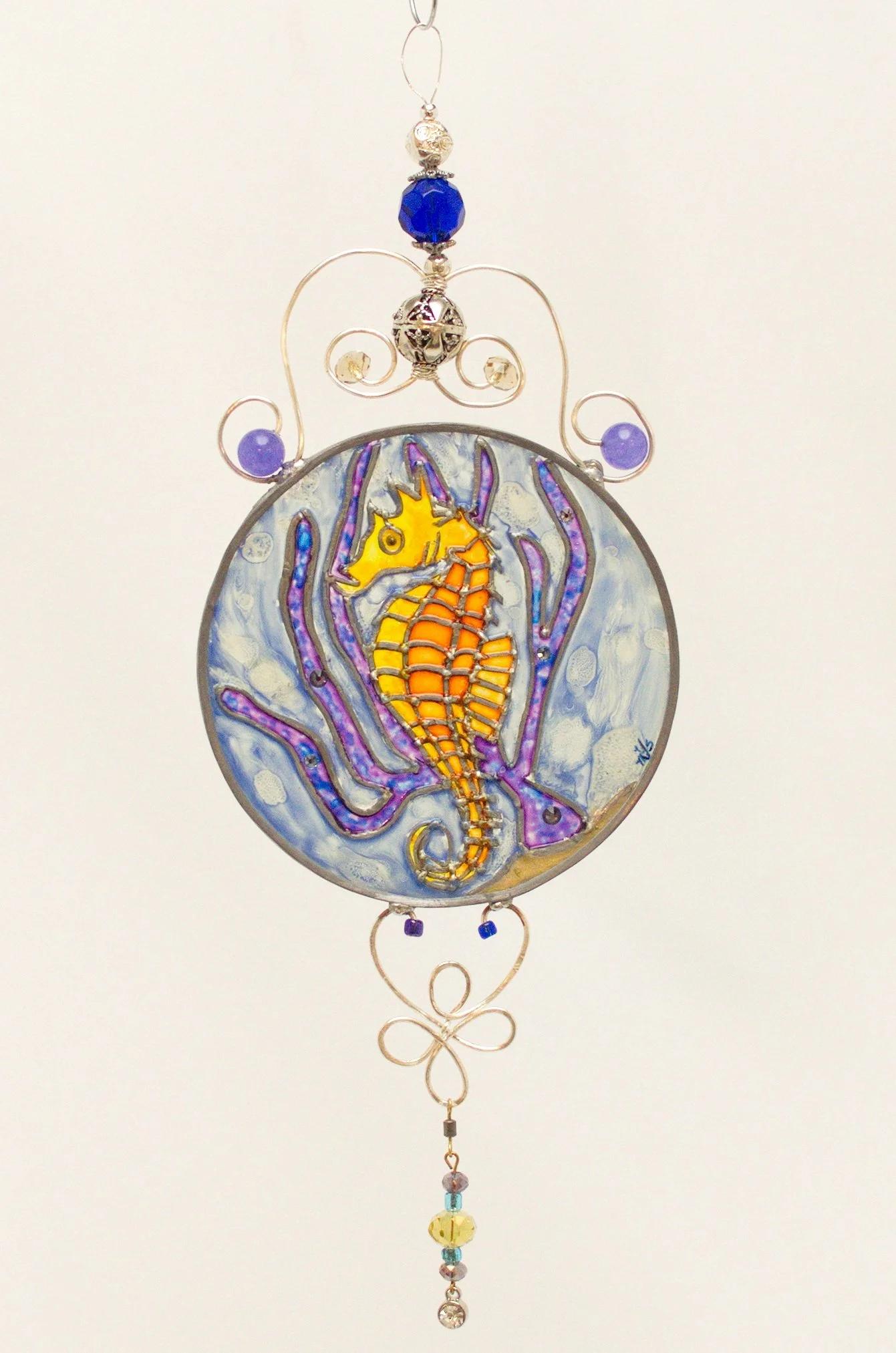 🔴 Sold: 
Seahorse Illusion Glass by Art Illusions by Young. A delicate seahorse floats among coral and sea plants in this round suncatcher, rendered in shades of blue, purple, and gold with sparkling bead accents. The underwater scene glows with eth
