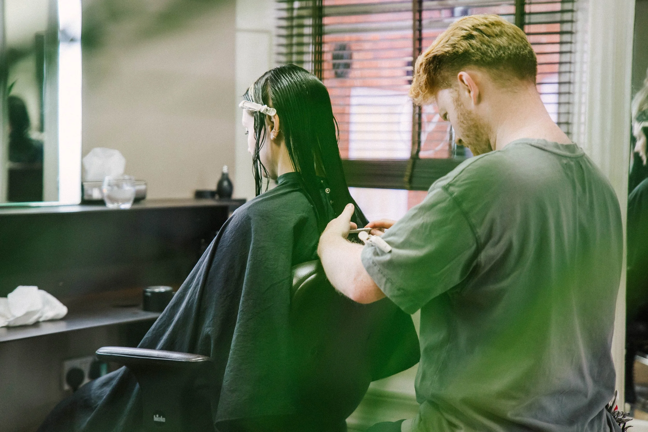Hairdresser cutting a woman's wet hair in a salon.
