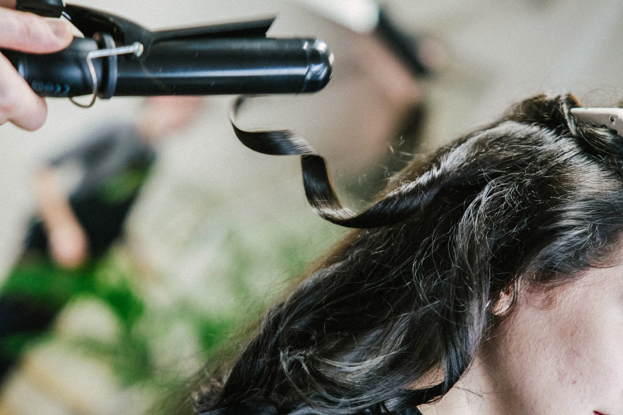 A person getting their hair curled with a curling iron.