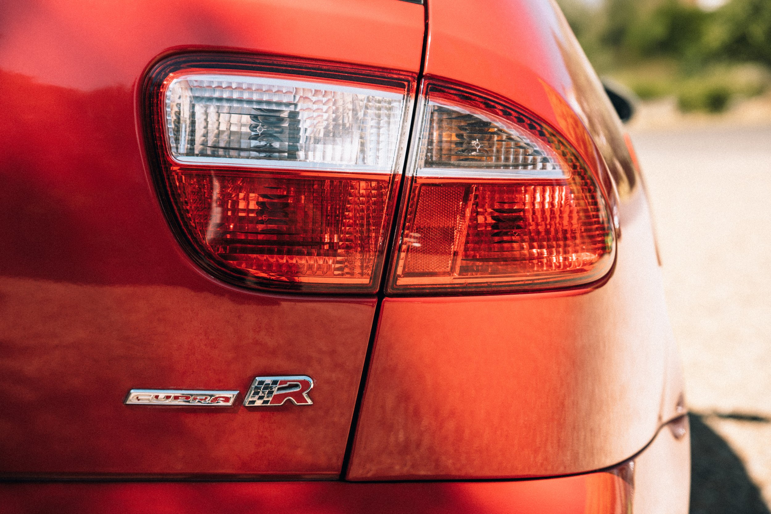Close-up of the rear taillight and badge of a red SEAT Leon Cupra R car.