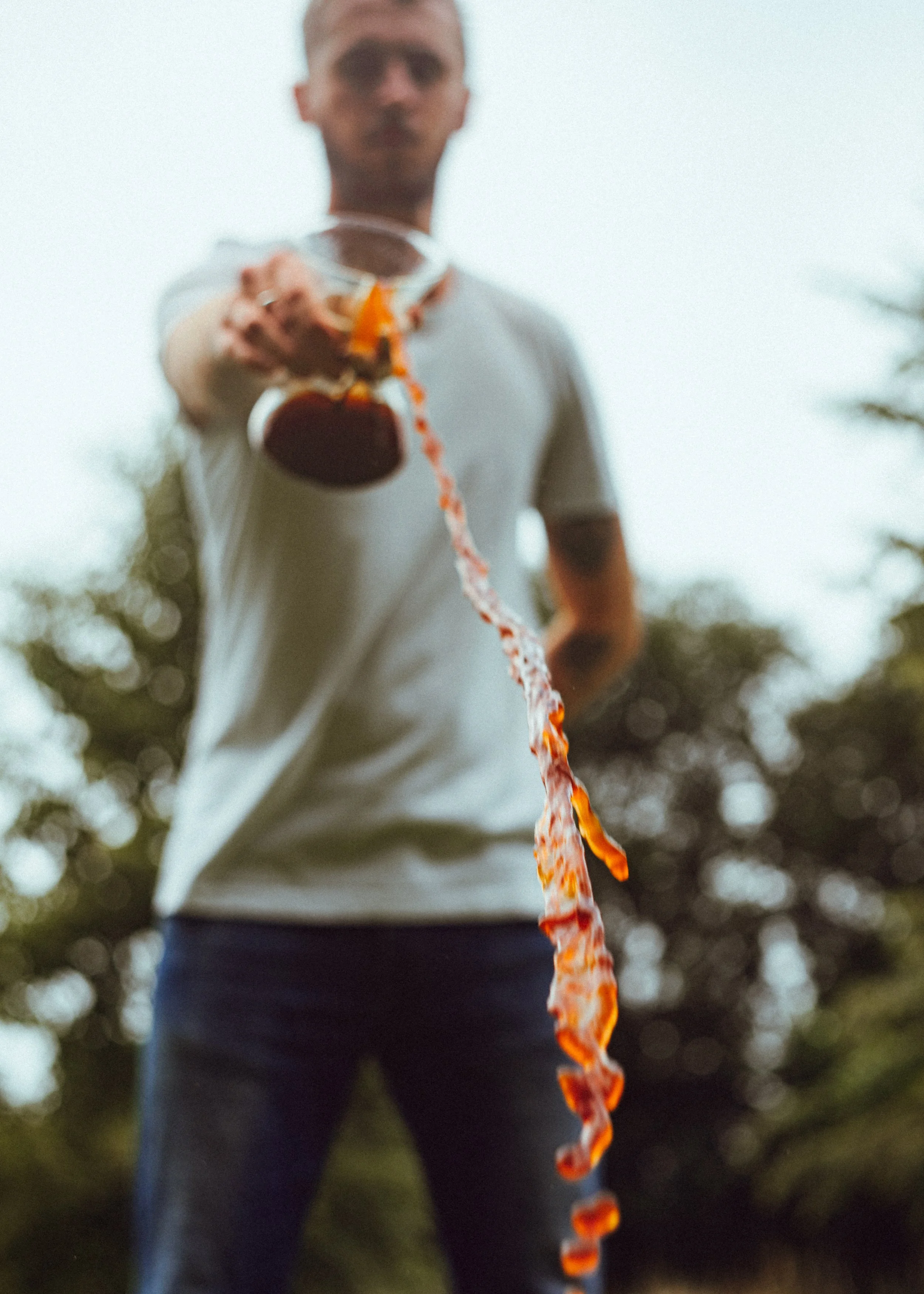Blurred man outdoors pouring liquid from a glass container