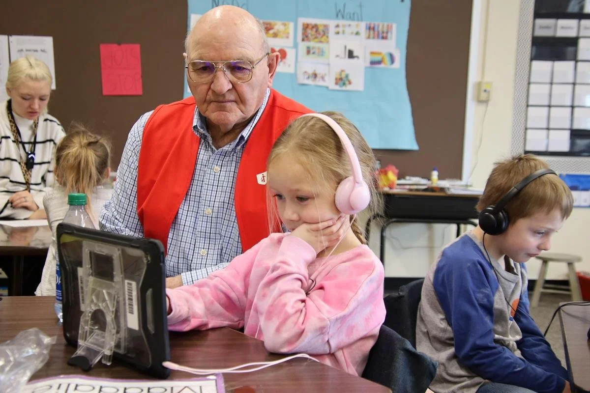 Grandparent reading with young children during an early learning activity that supports literacy development, family engagement, and positive relationships.