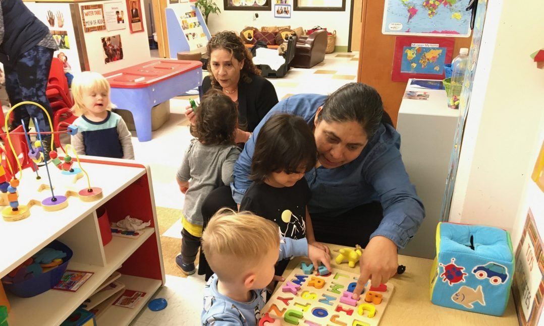 Parent participating in a hands-on early childhood learning activity with children using practical, play-based strategies that support child development.