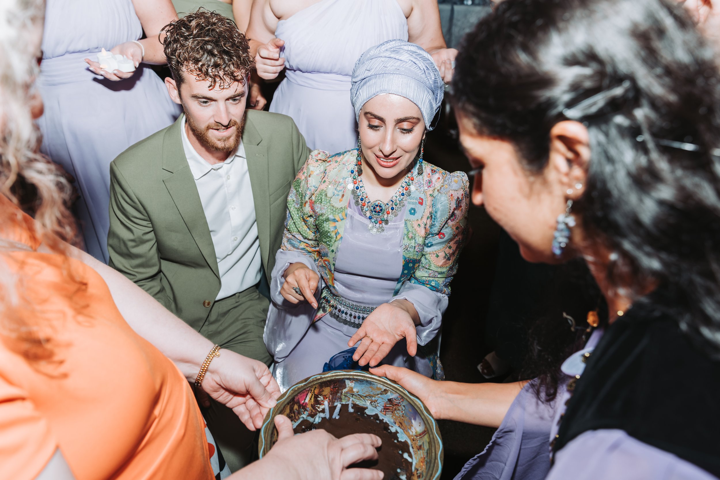 A group of people gathered around and examining a decorated cake or pastry with chocolate topping.