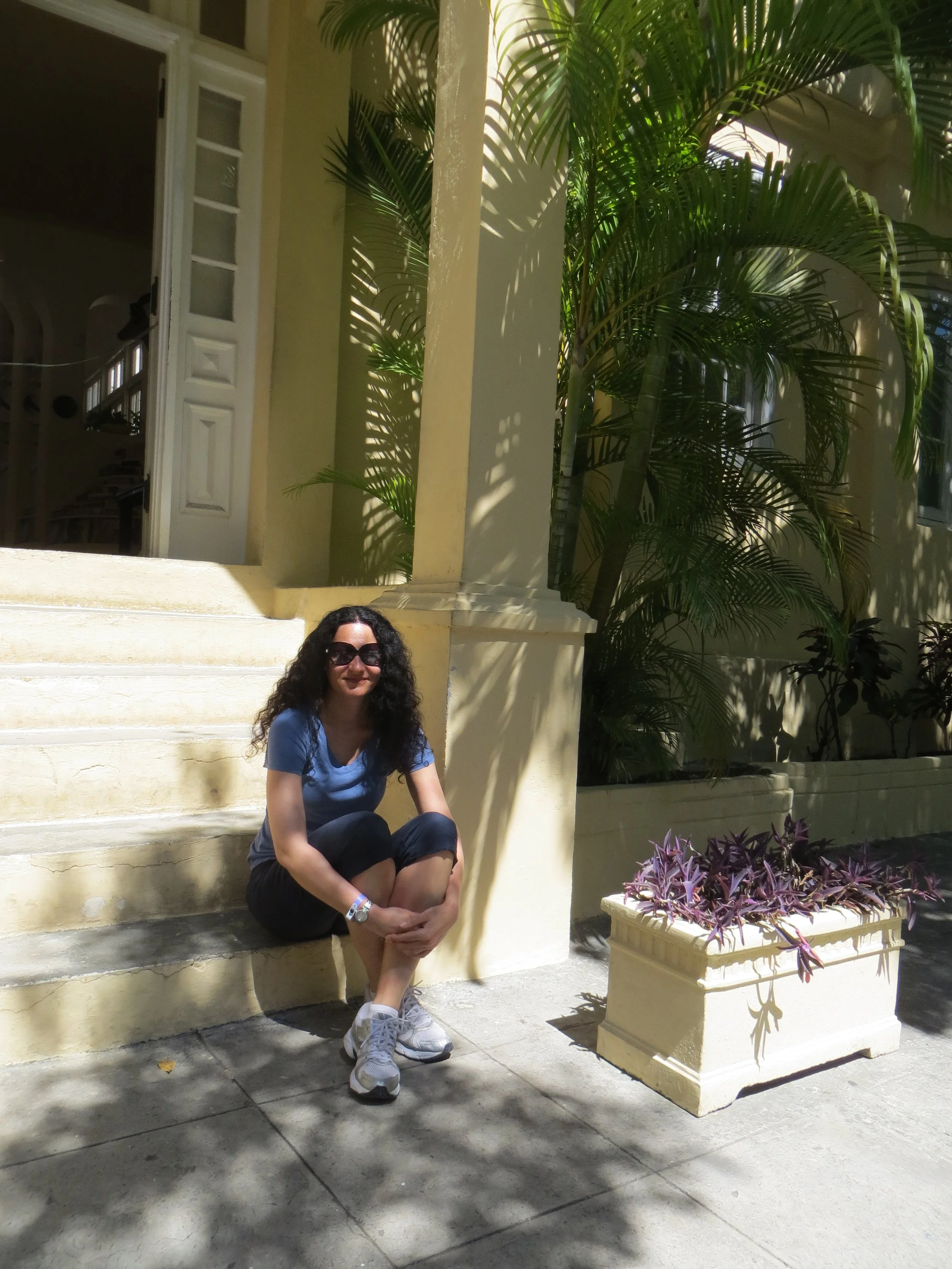 Stasha is sitting on the steps in front of the house.
