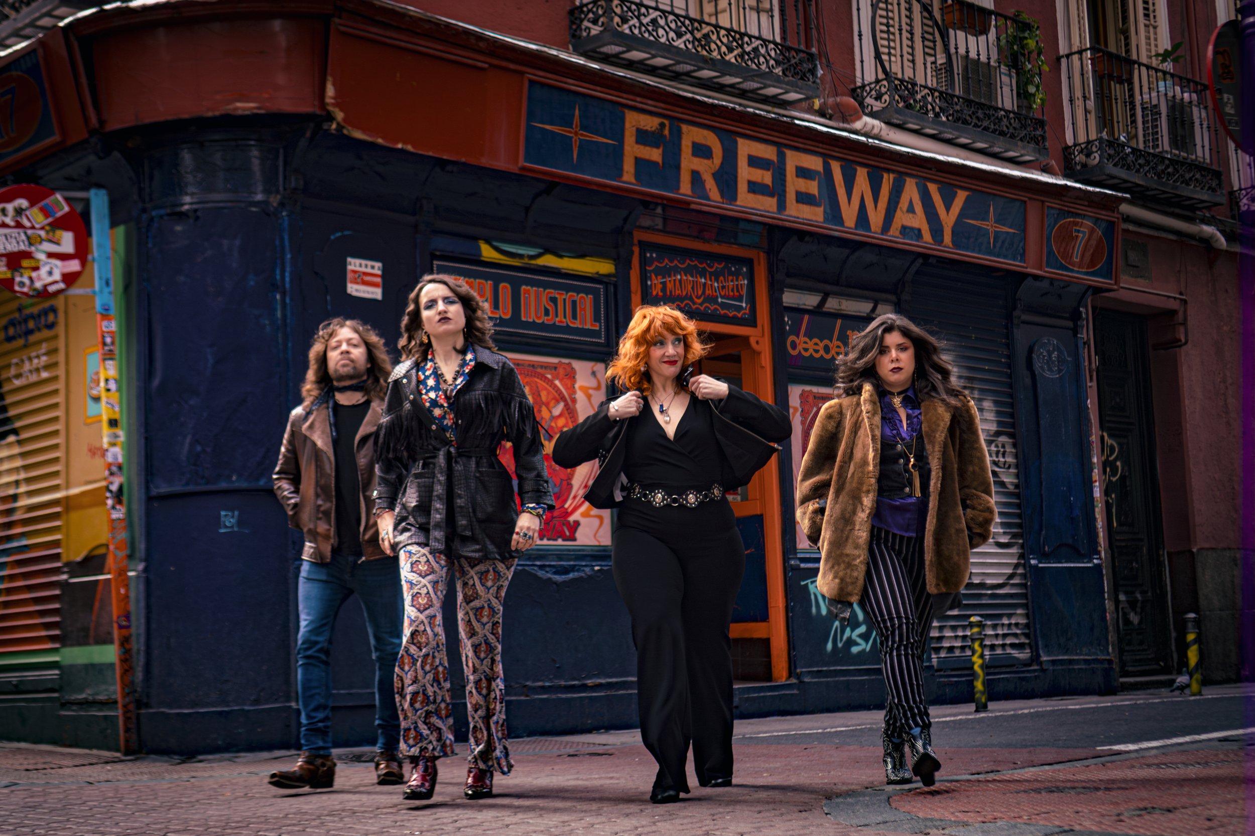 Cuatro personas caminando frente a un teatro cerrado con cartel que dice 'FREEWAY' en una calle urbana