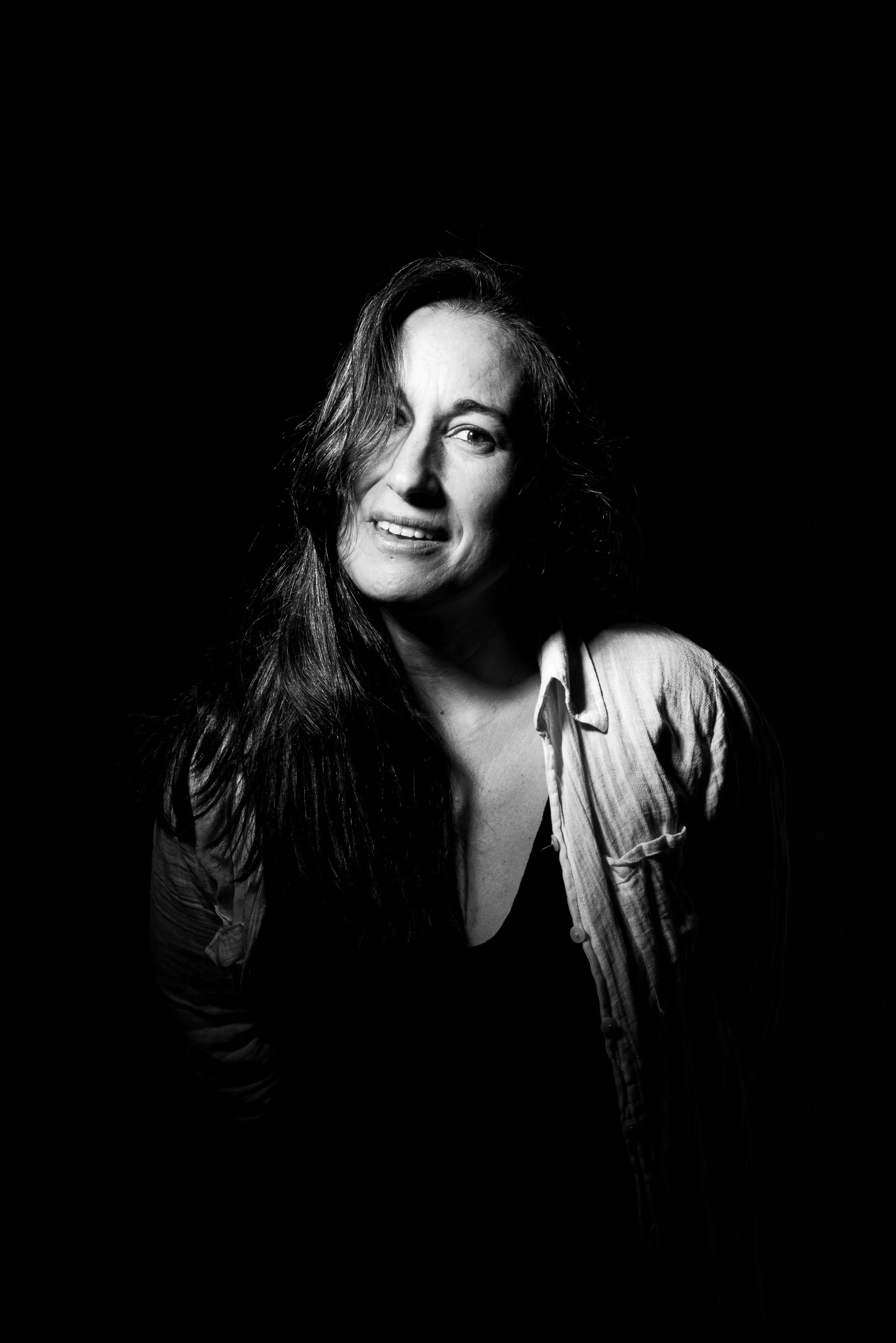 Retrato en blanco y negro de una mujer con cabello largo, vestida con una camisa, y haciendo una expresión facial de confusión o duda.