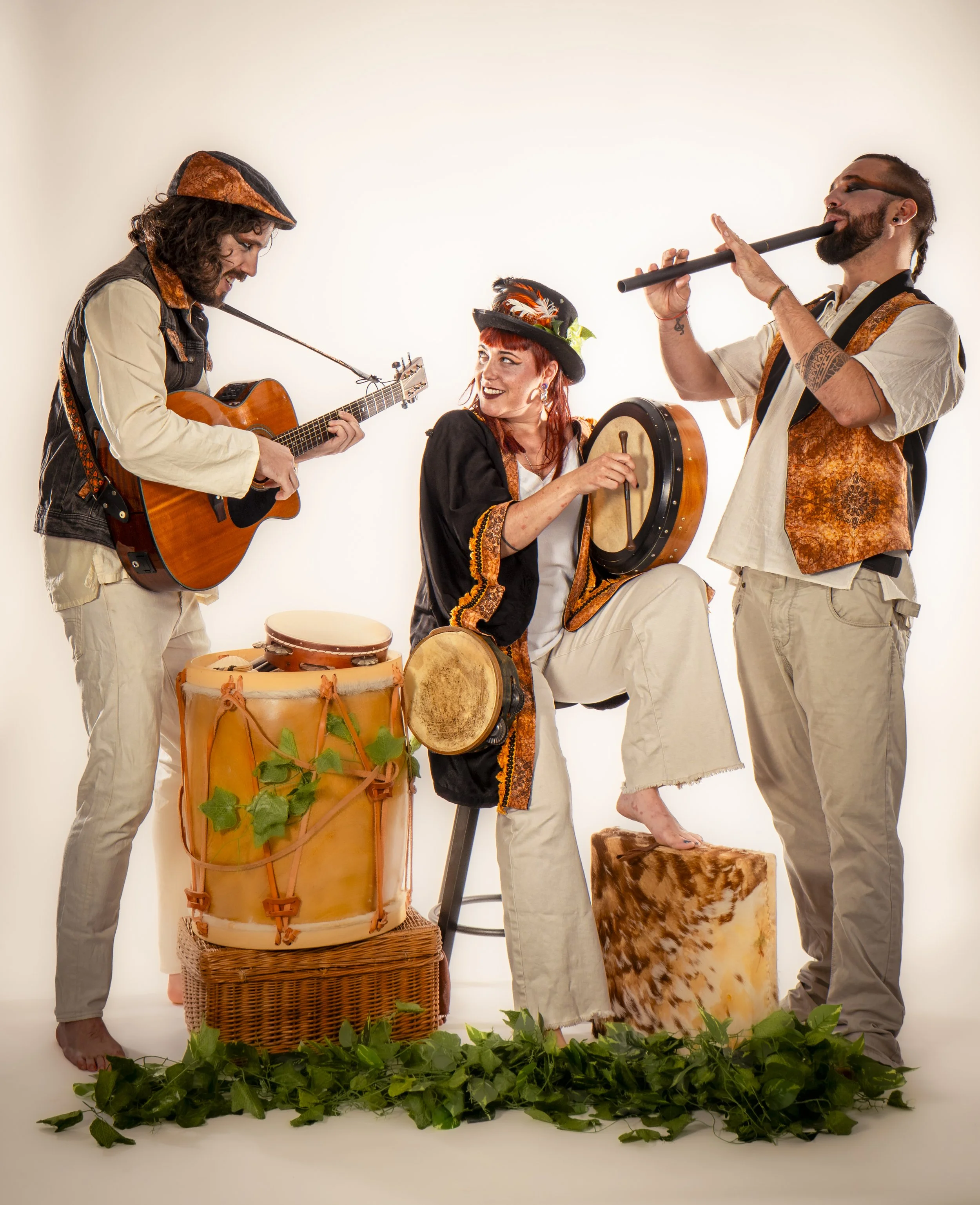 Tres músicos tocando instrumentos tradicionales, con decoraciones florales y de animales, en un escenario con fondo blanco.