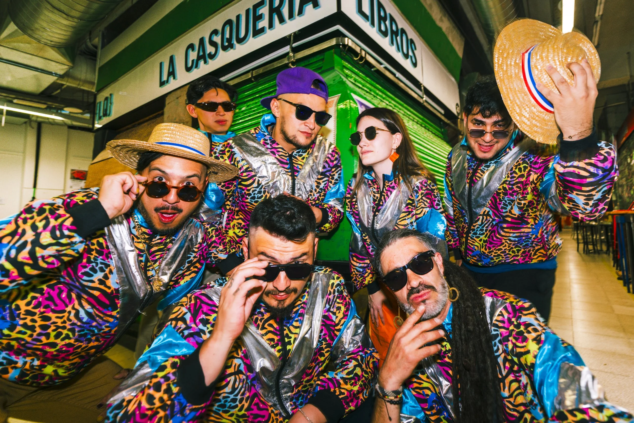 Grupo de personas con ropa colorida y gafas oscuras en un lugar cerrado.