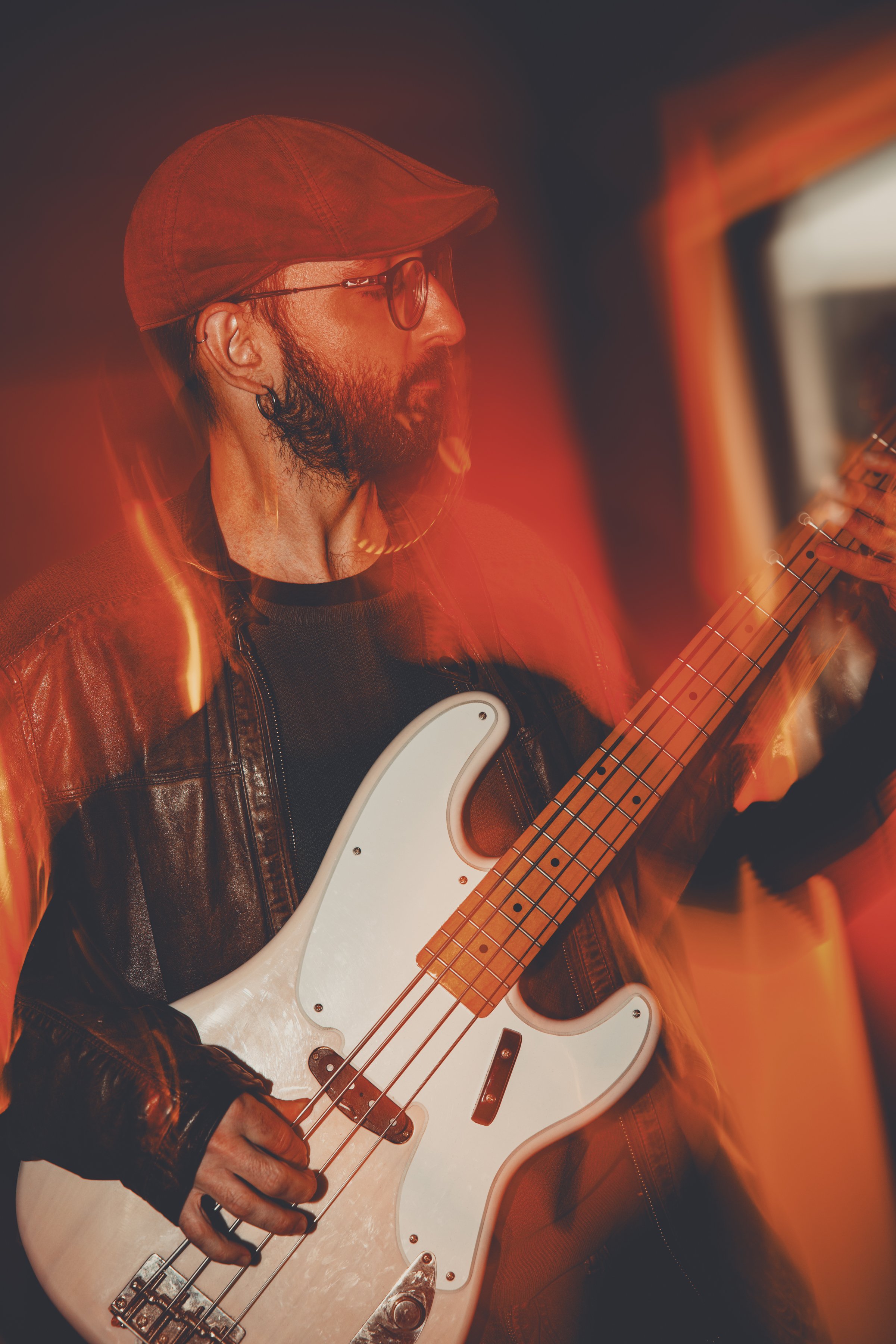 Hombre tocando guitarra eléctrica en un ambiente con iluminación roja y efecto de movimiento.
