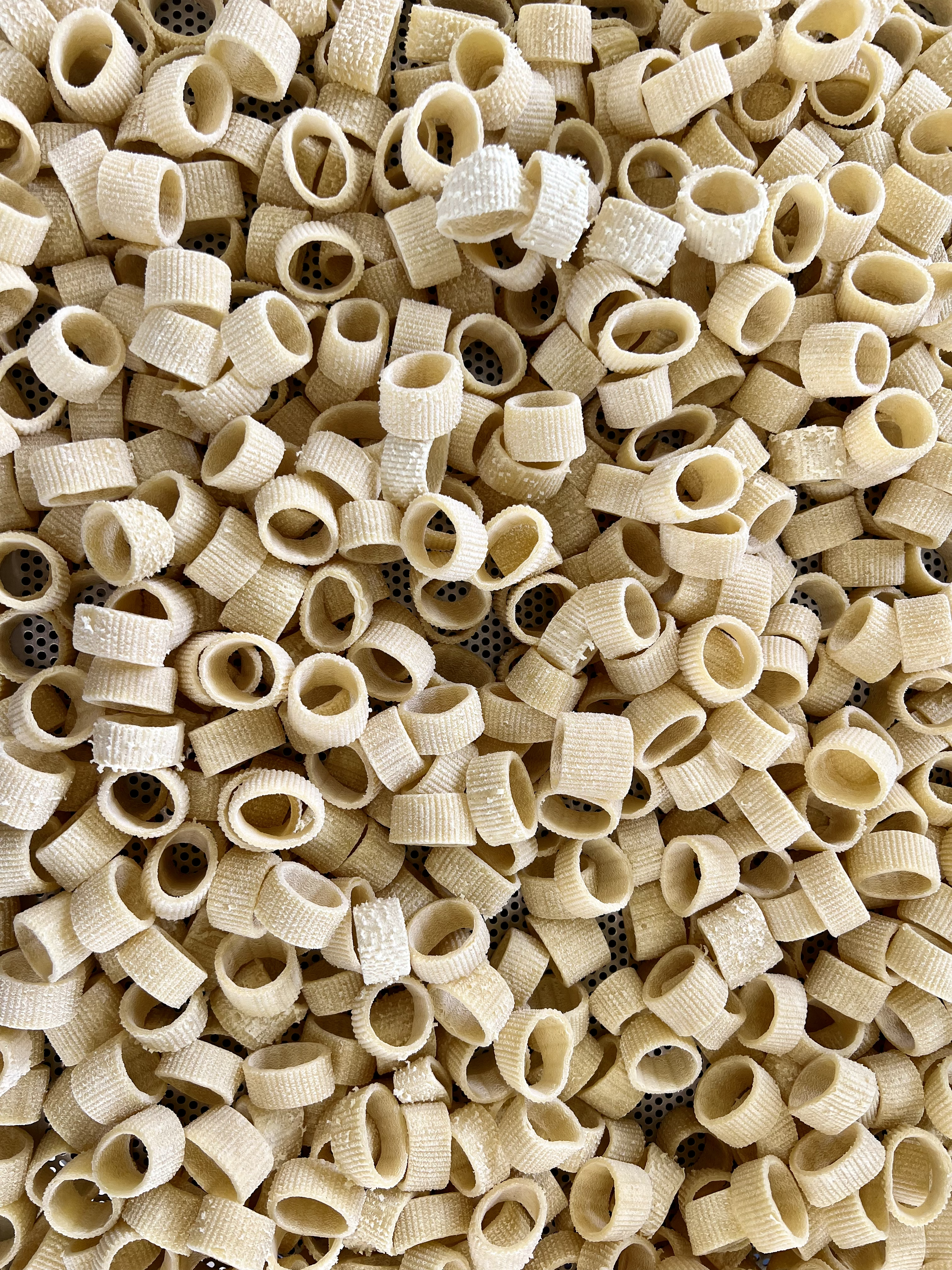 Close-up of uncooked pasta in a colander.