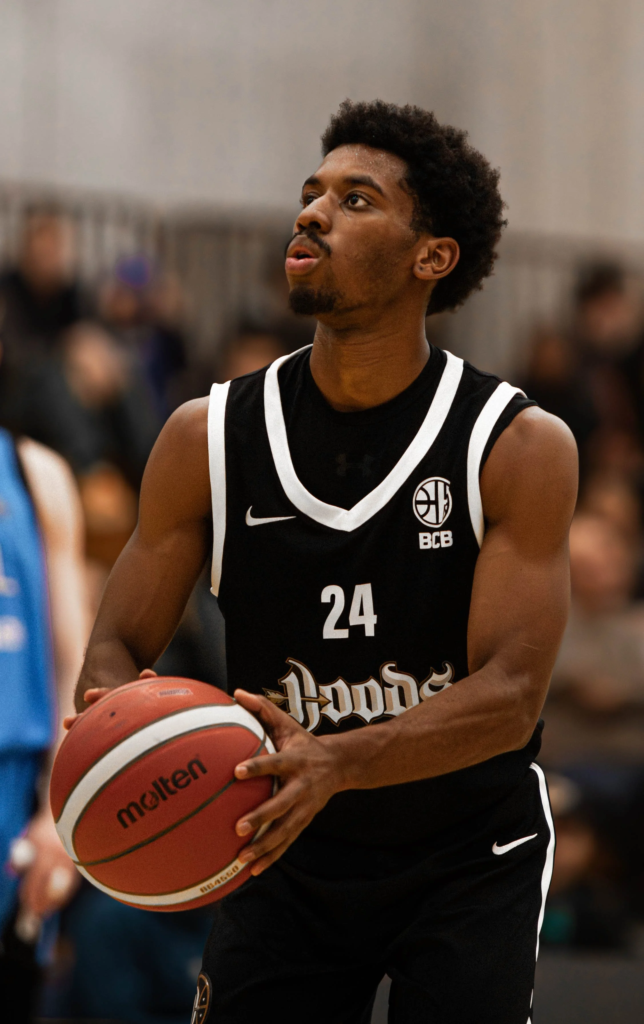 A basketball player in a black jersey with the number 24 holding a basketball on a court.