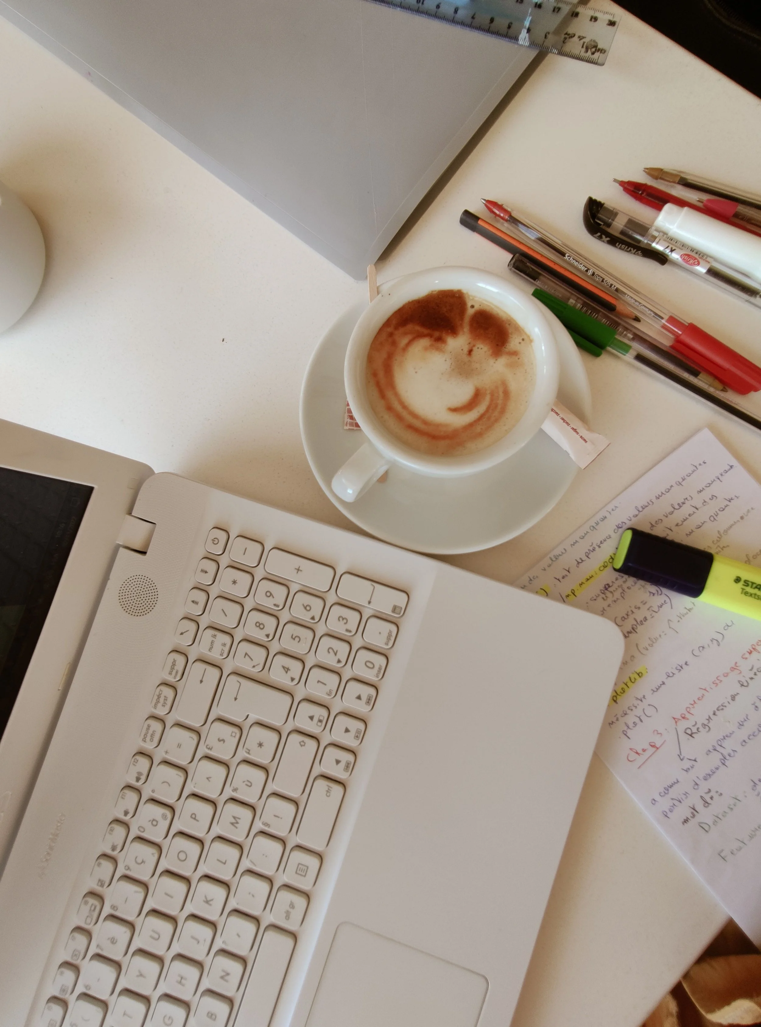 An overhead view of a cluttered desk with notebooks, sticky notes, and an open laptop, representing executive functioning challenges and task paralysis