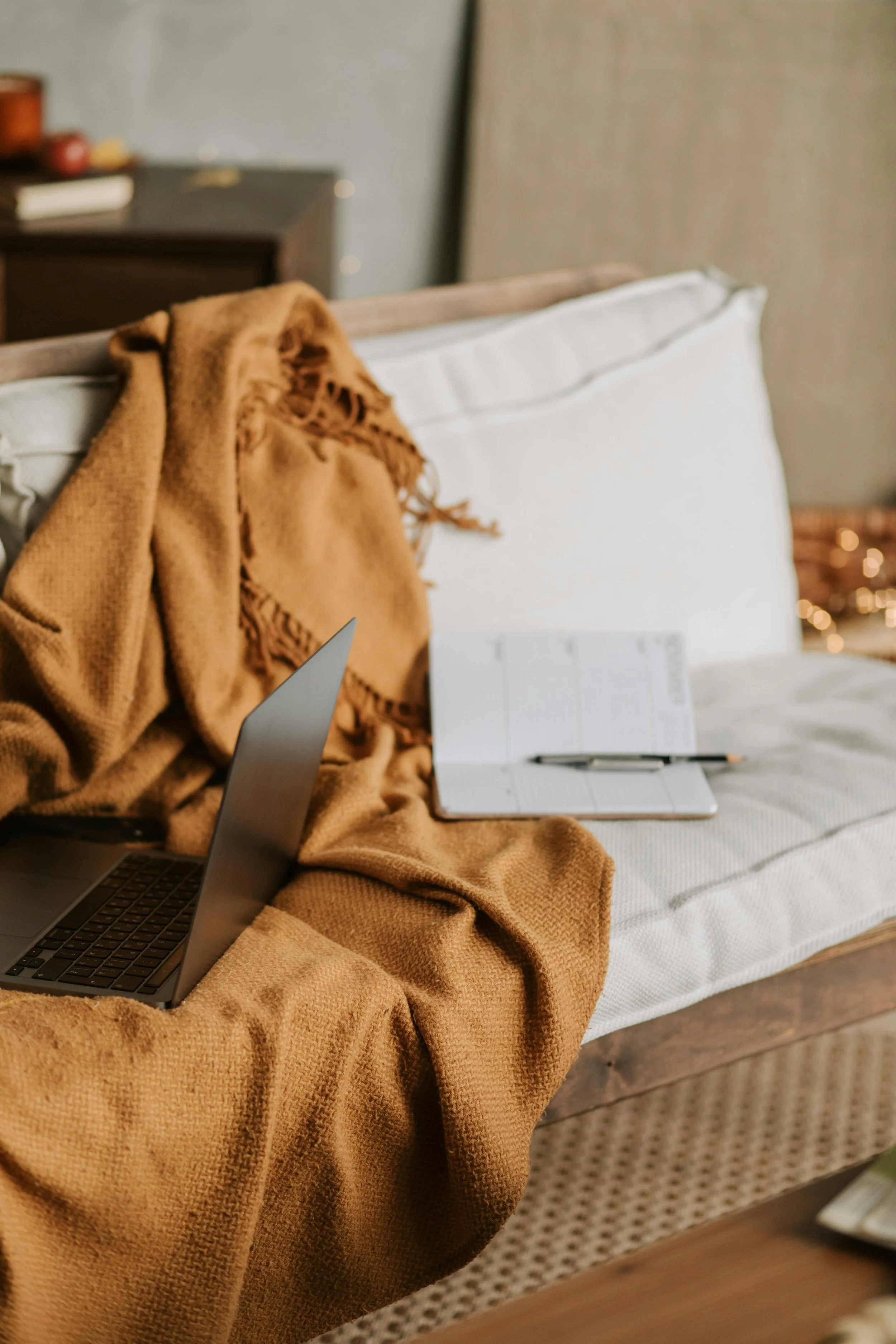 A laptop and notebook resting on a warm blanket, representing telehealth therapy available across Connecticut