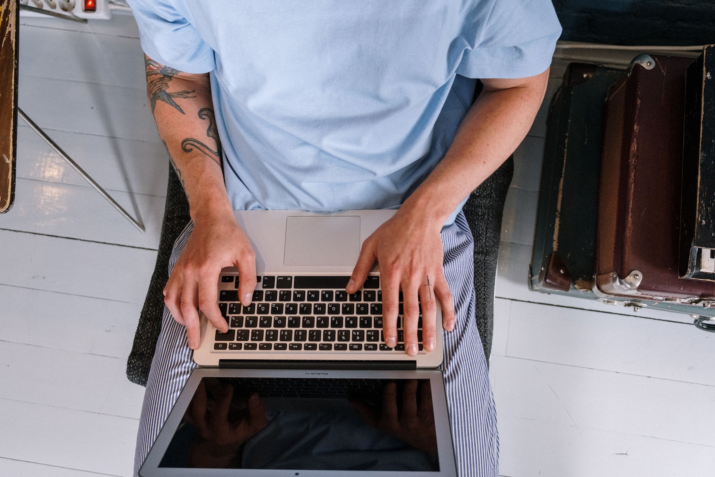 Overhead view of a person working at a laptop with a notepad nearby, representing the invisible labor and high-functioning performance that can mask burnout in adults
