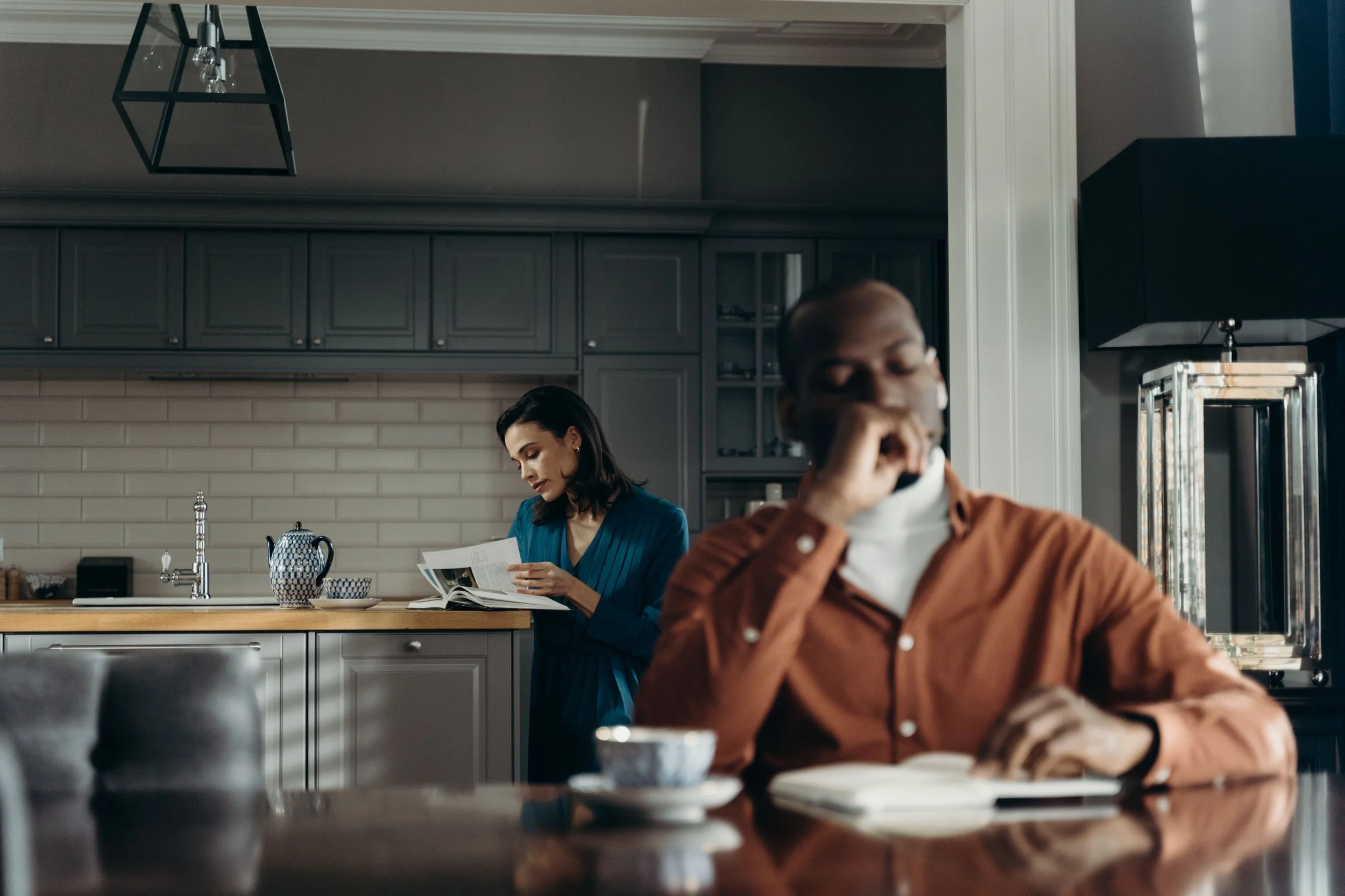A couple sitting on a couch with distance between them, representing the quiet disconnection that builds when overfunctioning and resentment go unaddressed in a relationship