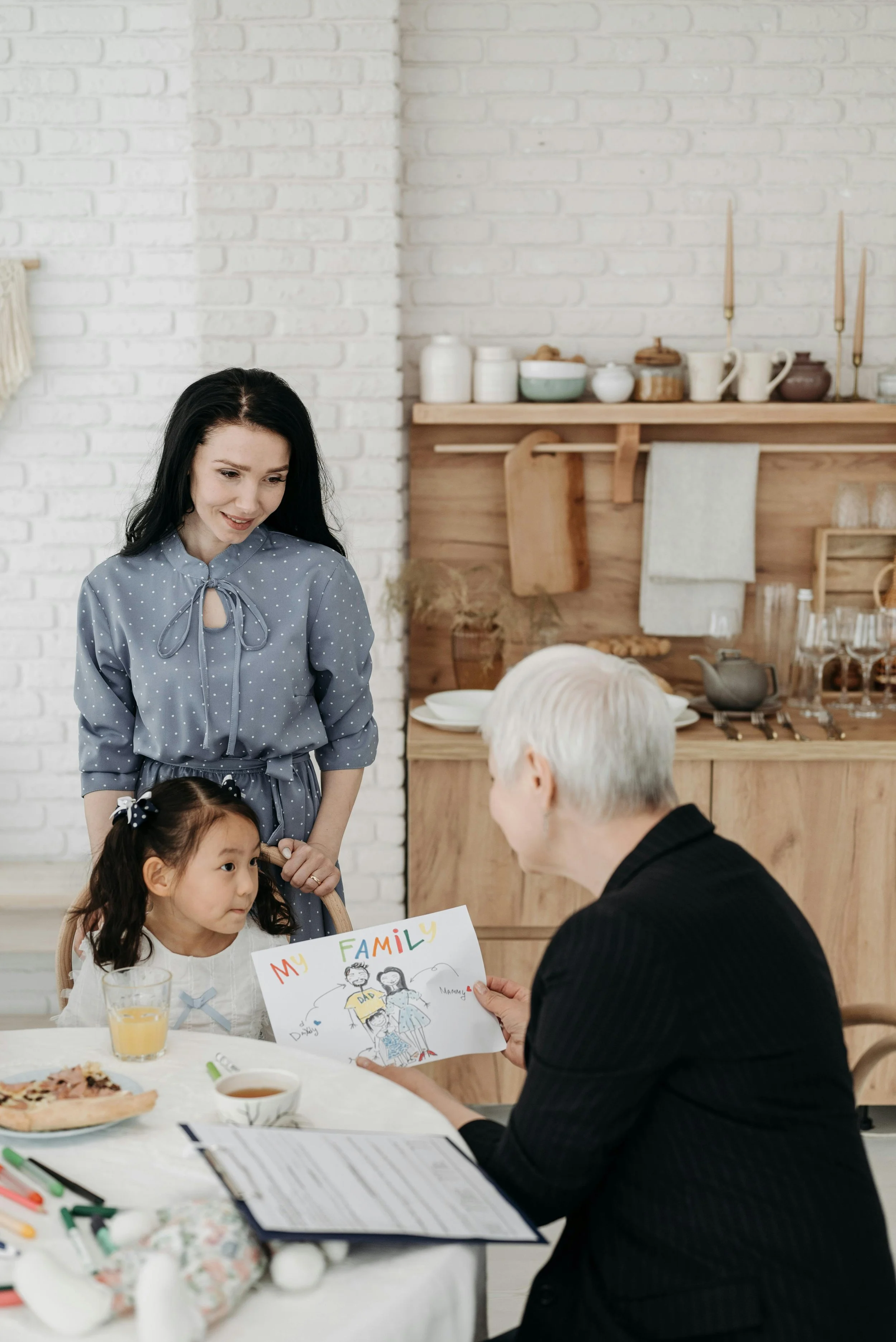 A mother, grandmother, and young child together at a kitchen table, representing generational trauma and cultural identity therapy in Connecticut