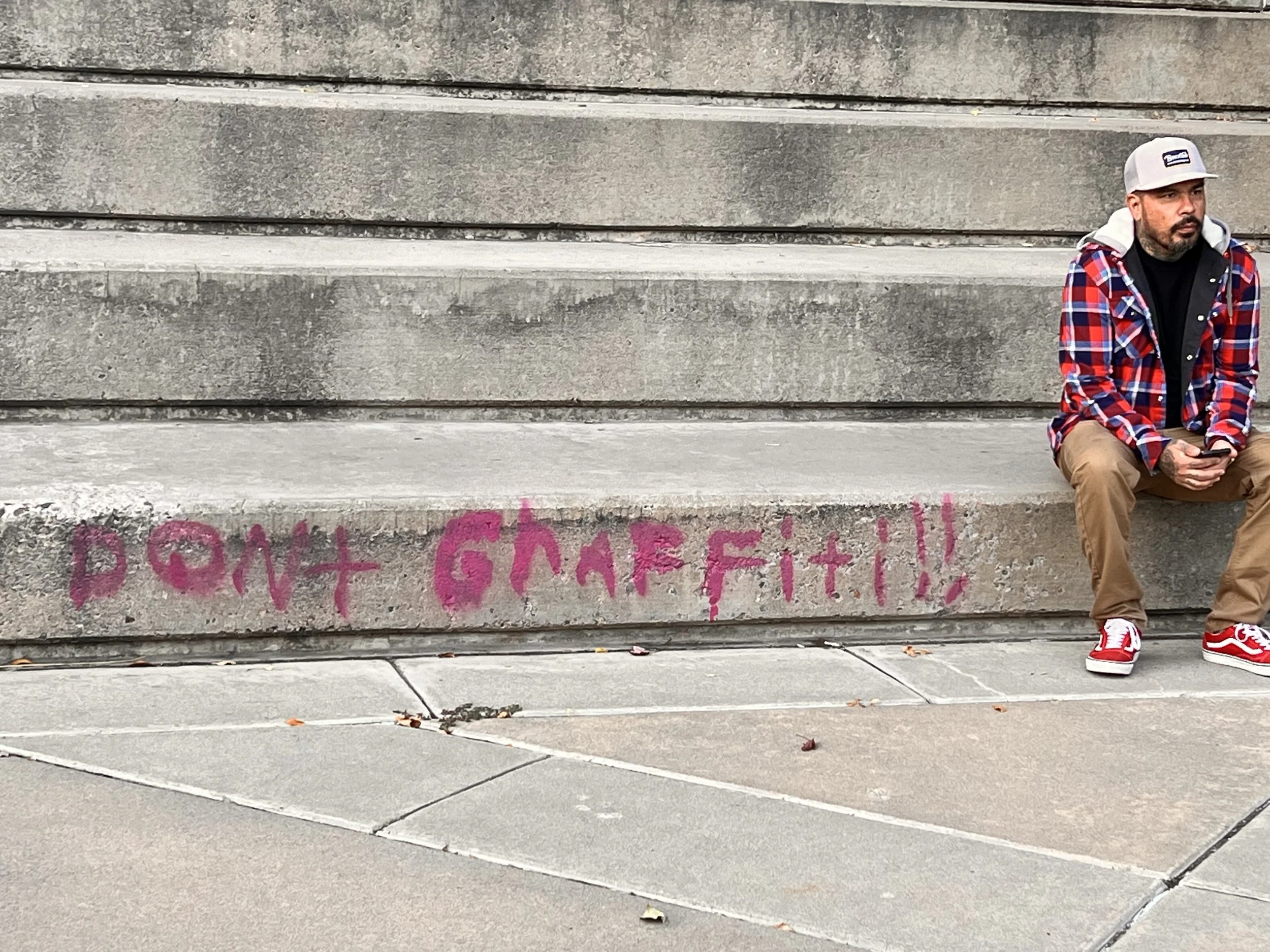 Jewp sits on steps pondering life next to a booty tag "don't Graffiti"