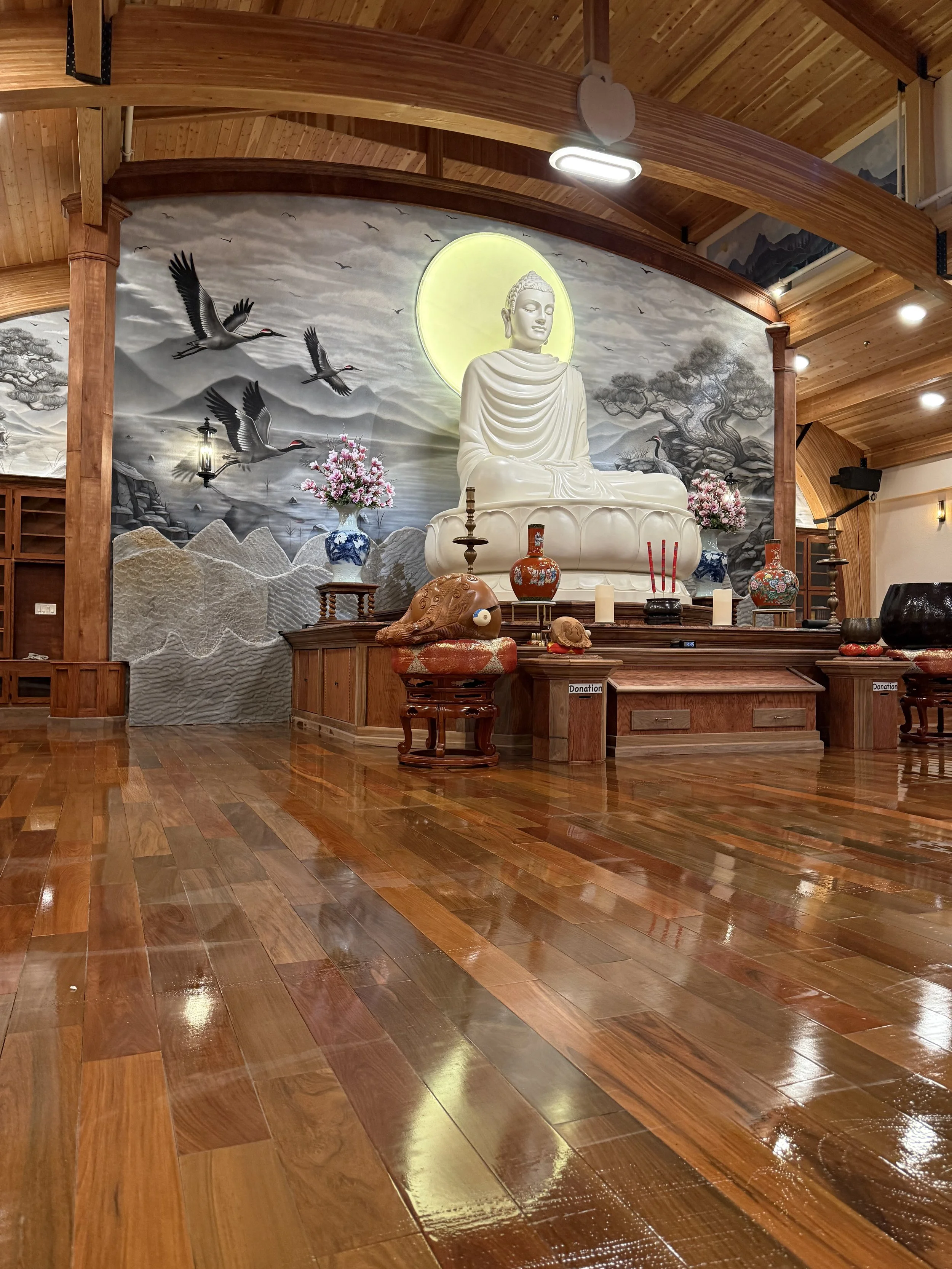 restored and painted Buddha statue mounted upon stage with crane and mural behind