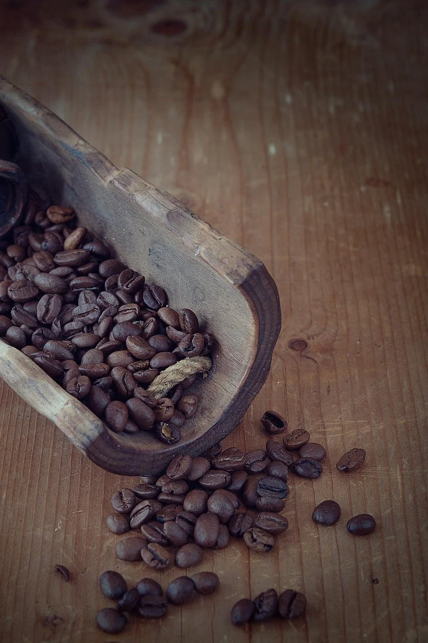 Image of a wooden half-circle bowl holding darkly roasted coffee beans.