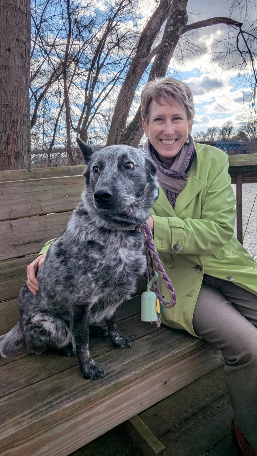 Lora on a bench with her dog overlooking the CT River
