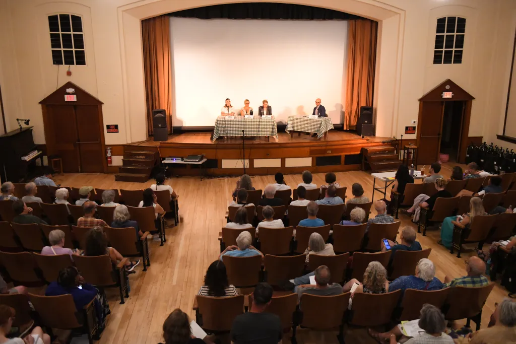 Voters watching a panel of 3 candidates with a moderator