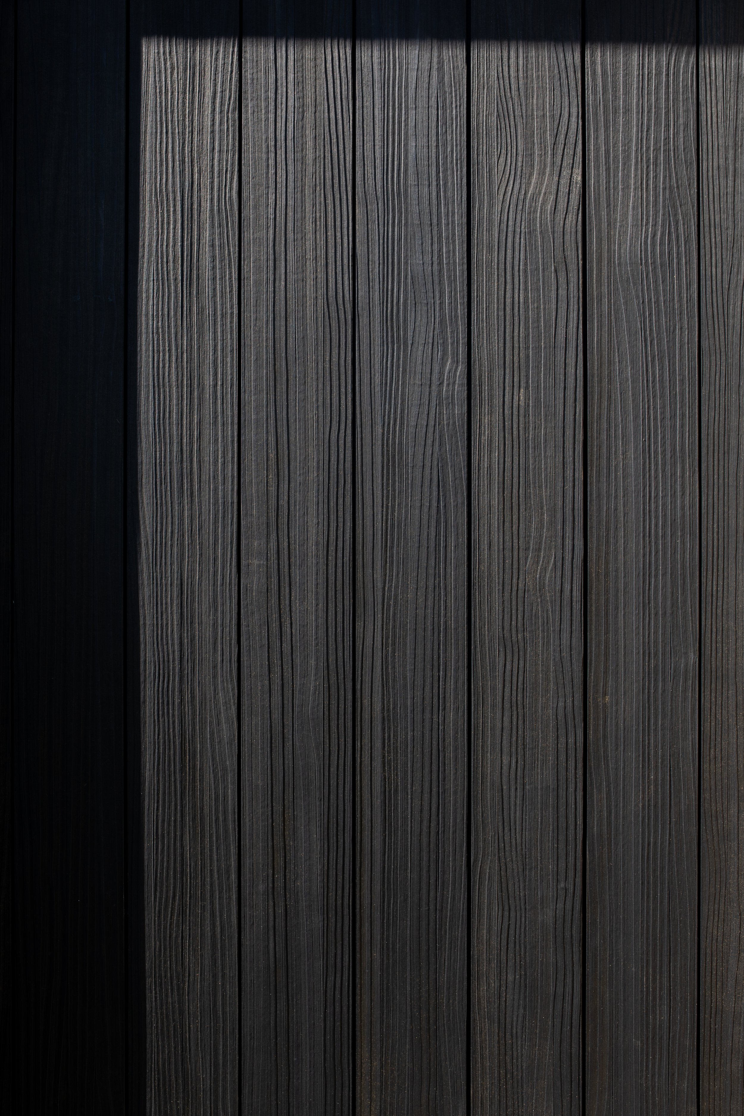 Close-up of vertically aligned dark wood planks with visible grain patterns.