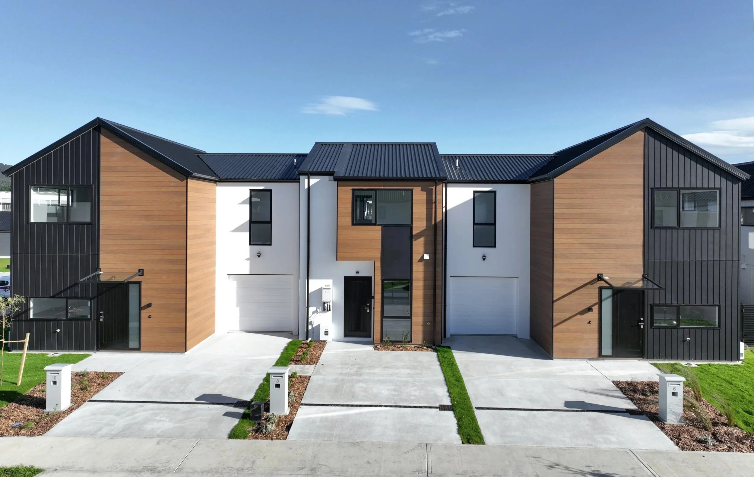 Contemporary Type F and Type A homes in The Reserve: Final Release, with black and wood siding, black roofs, concrete driveways, and small landscaped front yards.