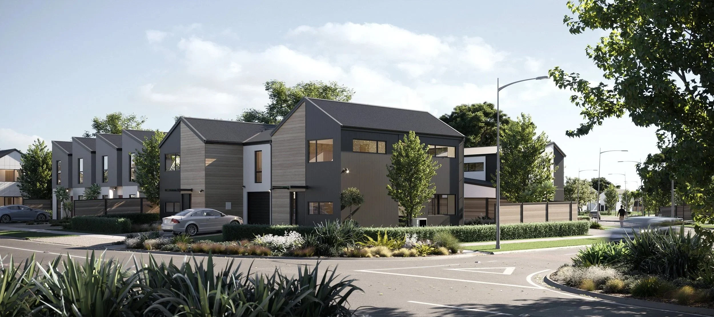 Modern residential neighborhood with contemporary houses, manicured landscaping, parked cars, walking pedestrians, and street lamps during daytime.