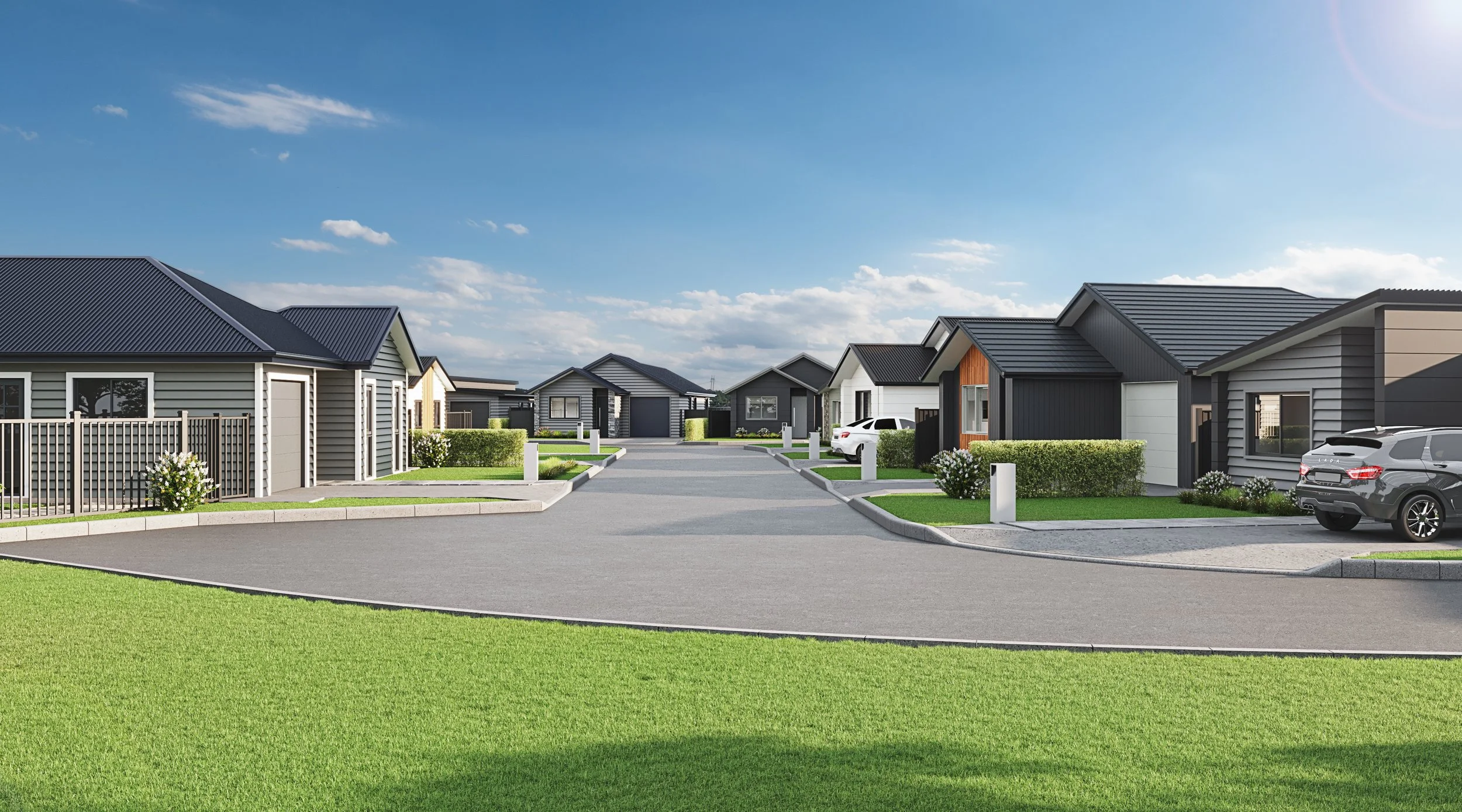 A suburban neighbourhood with modern homes, cars parked in driveways, green lawns, and a clear blue sky.
