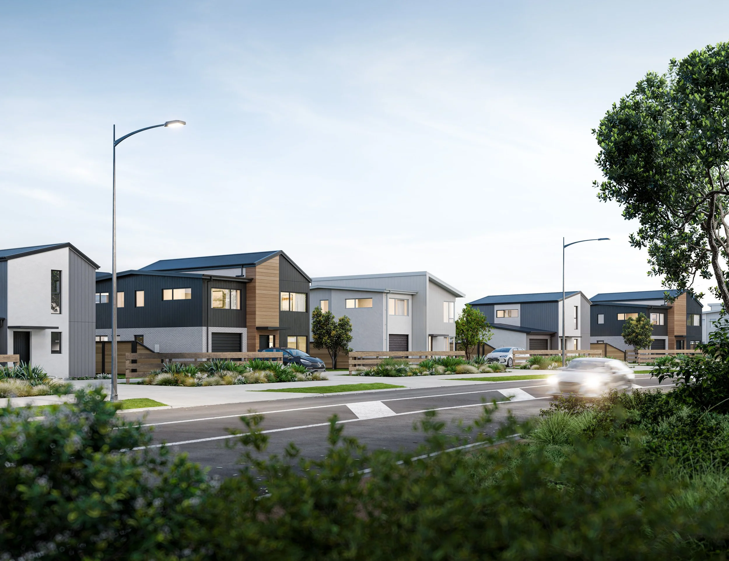 Modern suburban neighbourhood with contemporary houses, trees, streetlights, and a passing car on a sunny day.
