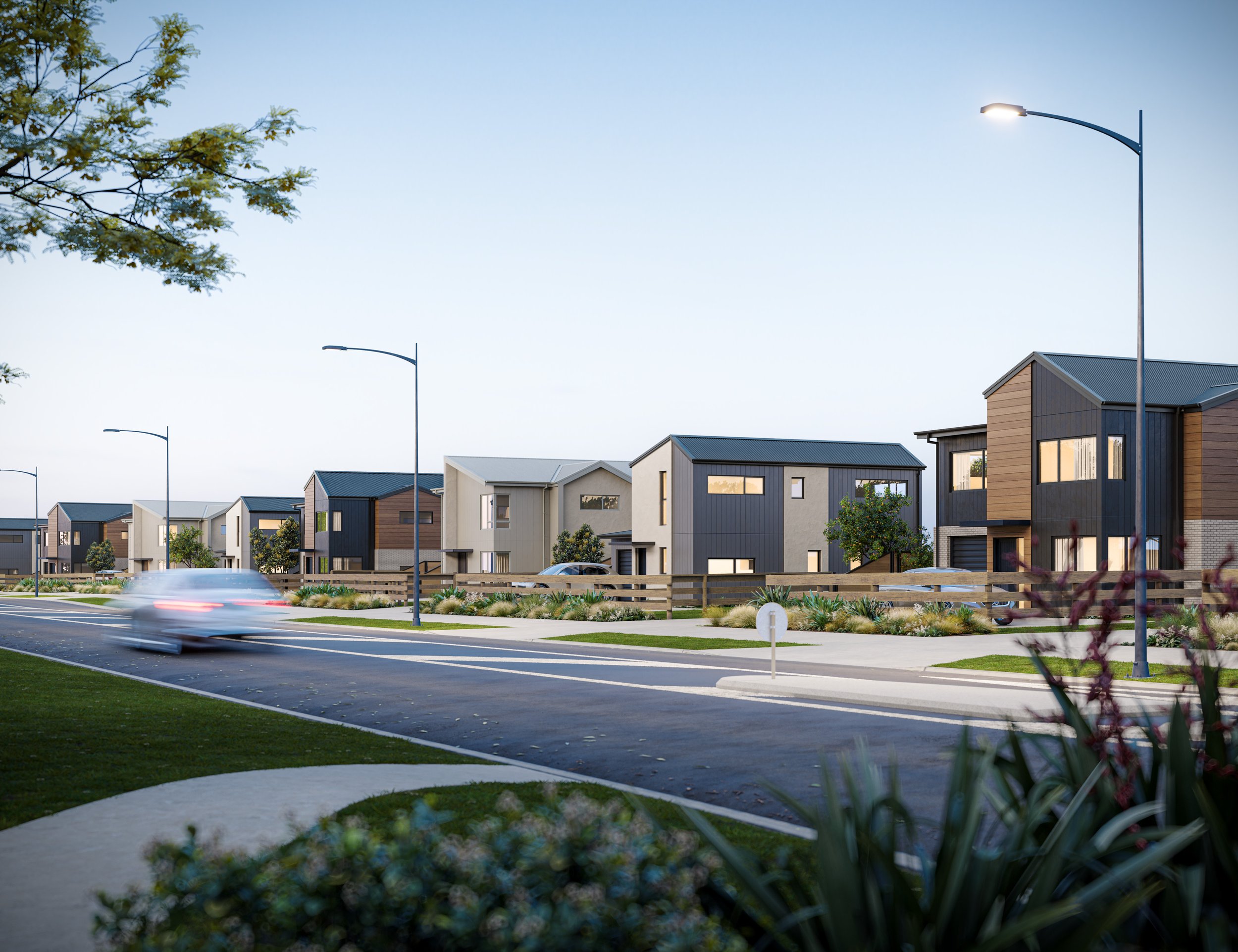 A modern suburban neighbourhood with new houses, a paved street, streetlights, and landscaped yards under a clear sky.