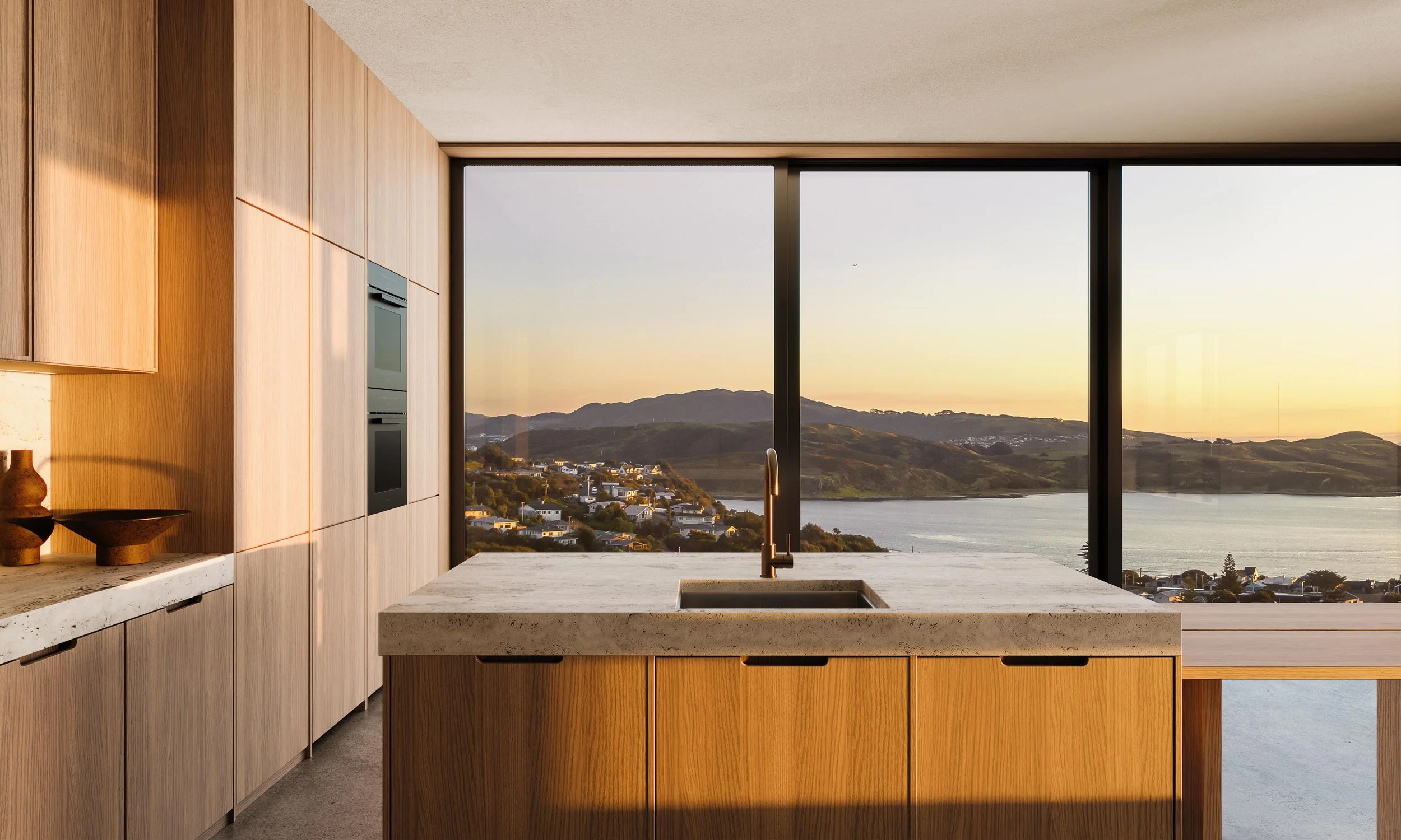 Modern kitchen with a view of a lake and hills through large windows, featuring wooden cabinets, a kitchen island with a sink, and minimal decor.