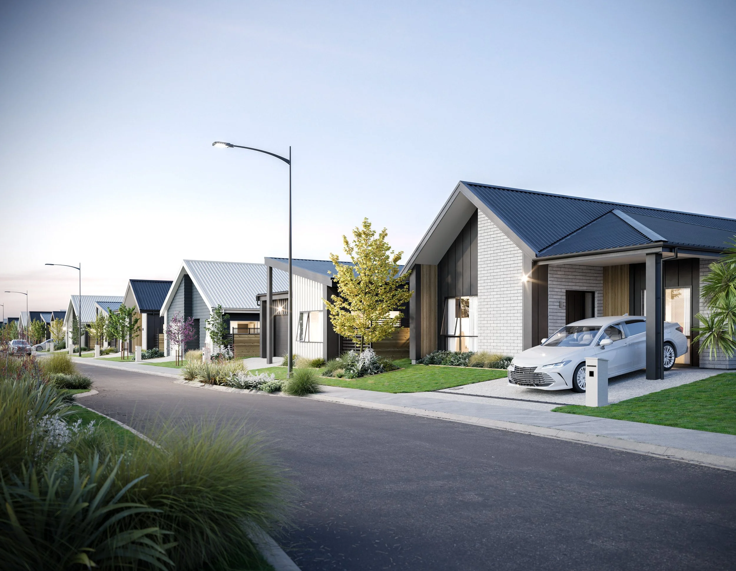 A row of modern suburban houses with manicured lawns and a paved street. Each house has a distinct design with mixed materials, including brick and wood, and features a driveway, some with cars parked.