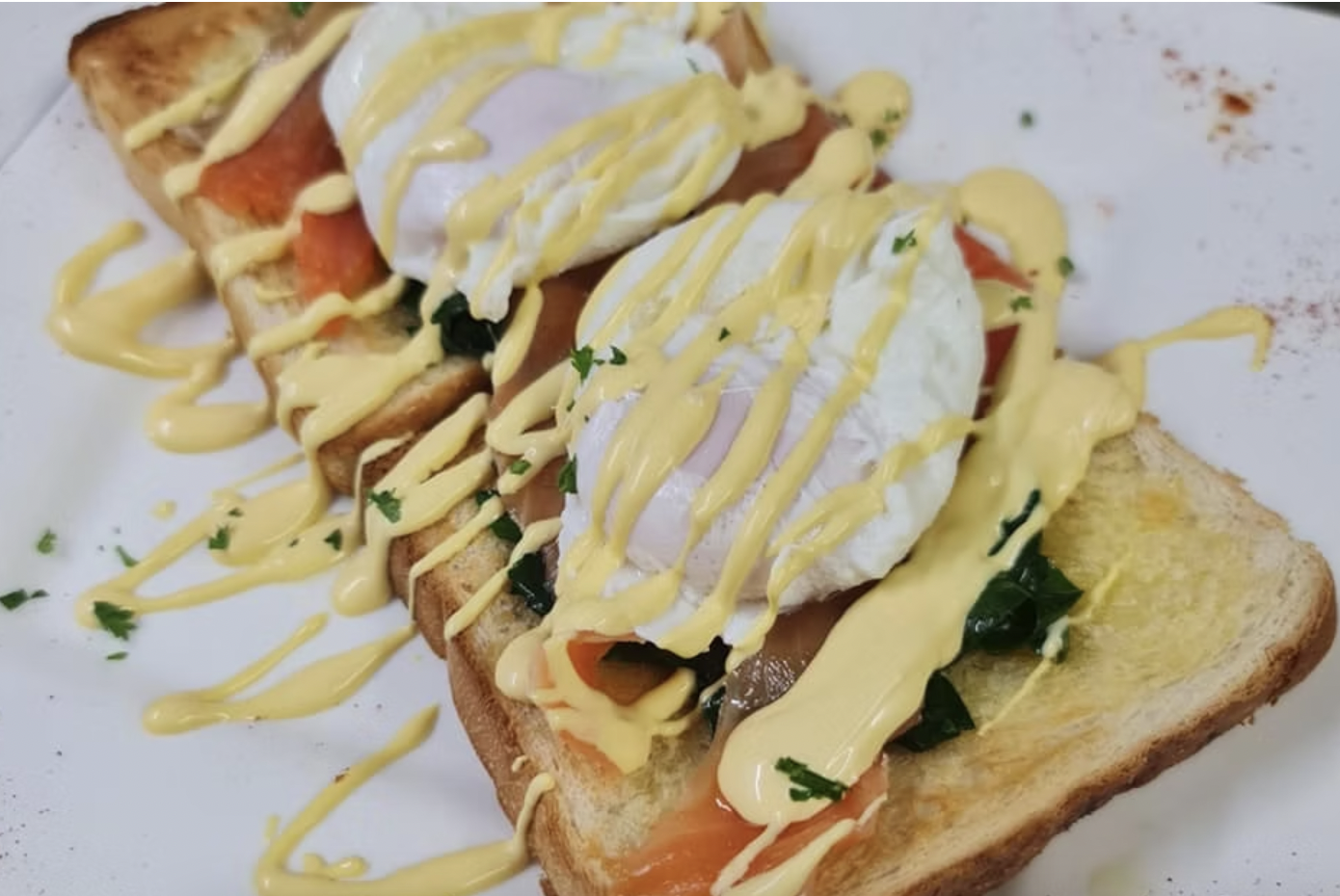 Poached eggs on toast with smoked salmon, herbs, and honey mustard drizzled on top.
