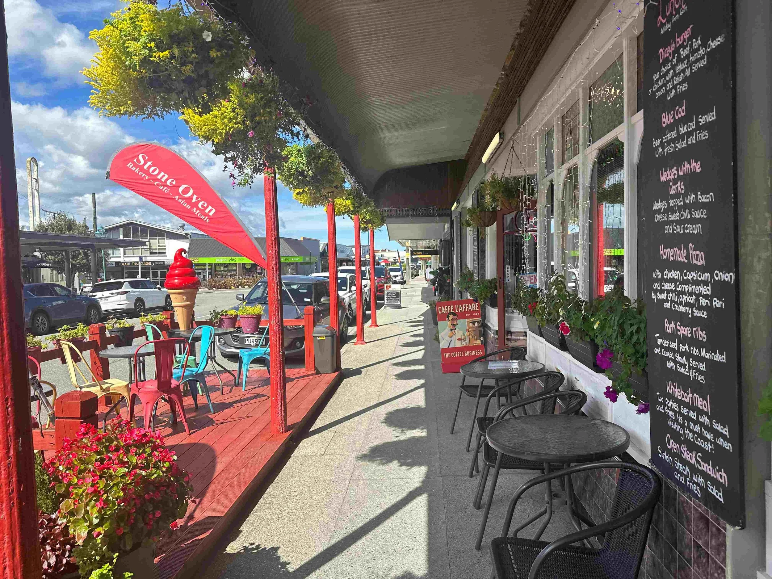 Sidewalk cafe with colorful chairs and tables outside stone oven bakery & restaurant entrance 