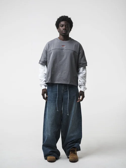 Front view ecommerce fashion photography of model wearing grey top and wide-leg jeans on white background