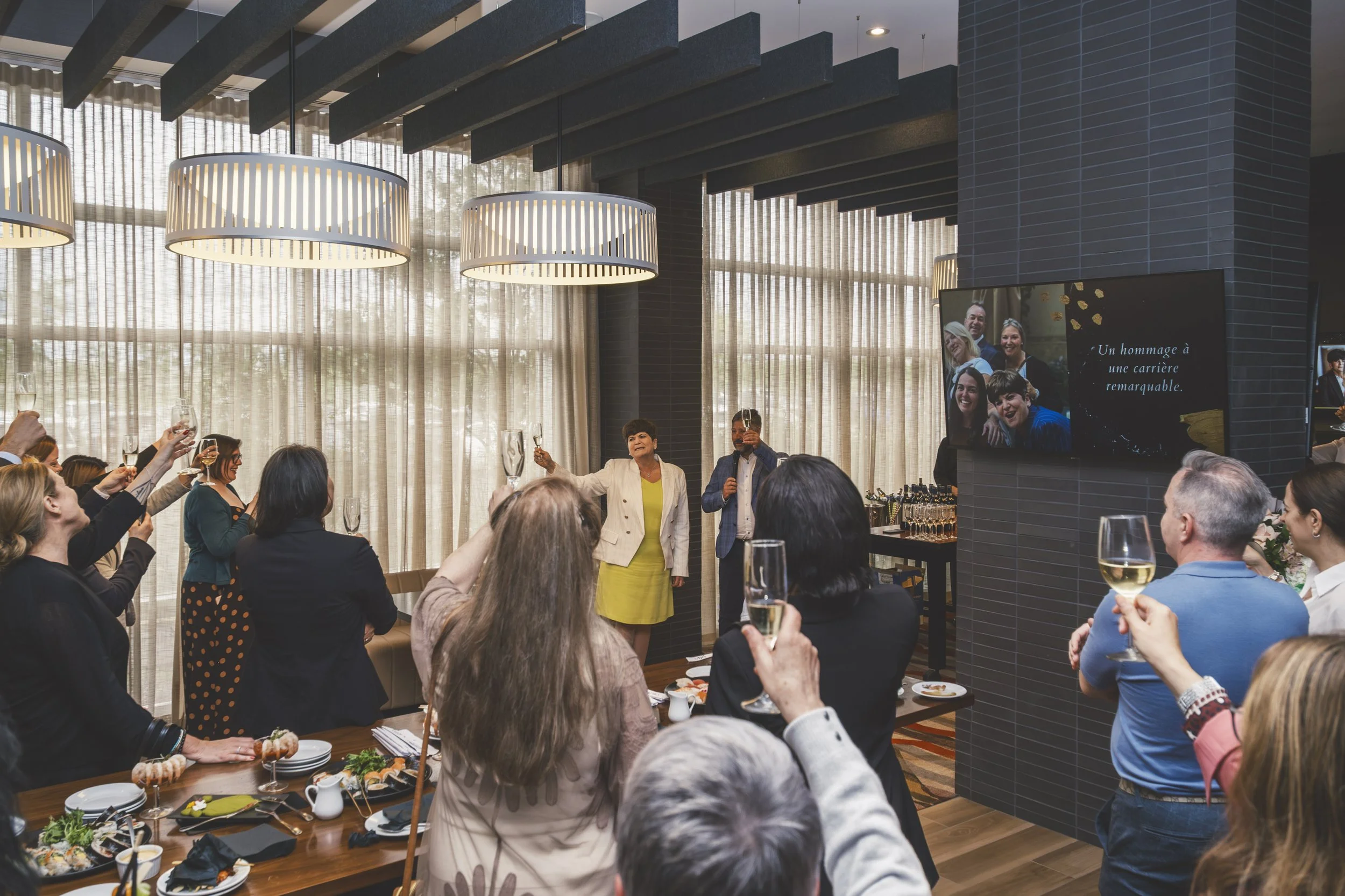 Wide event view with guests gathered around a retirement celebration presentation