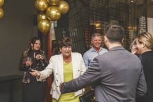 Guests posing together during Mirella retirement party in a warm event setting
