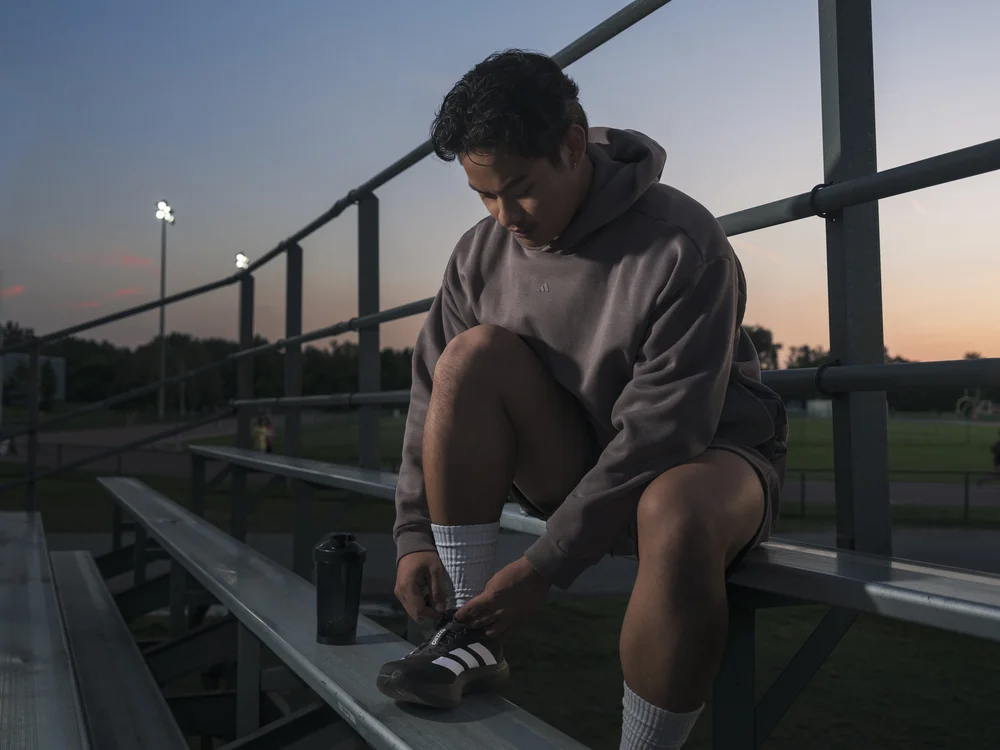 Fashion campaign photography of model sitting on bleachers in athletic apparel