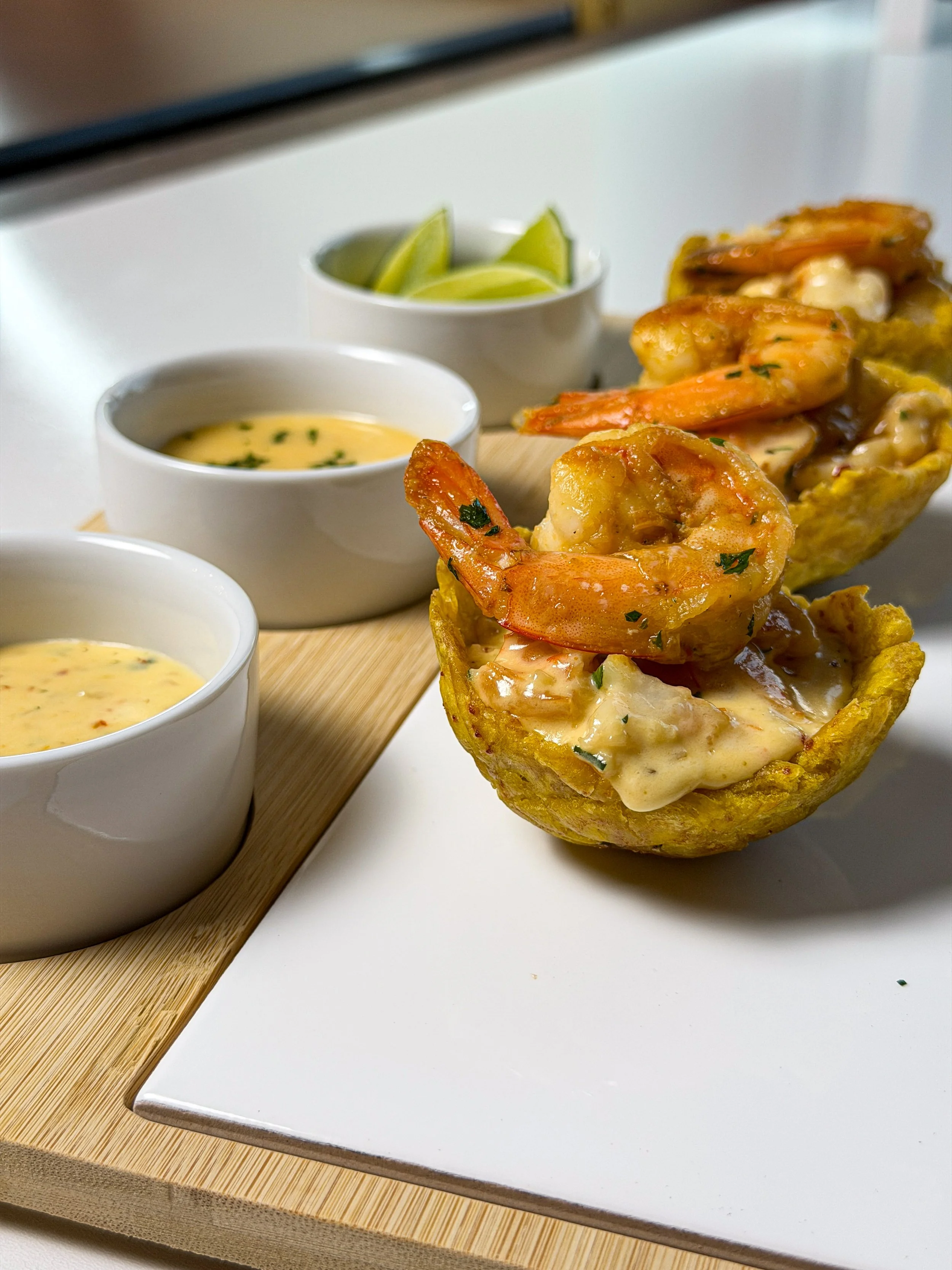 Shrimp stuffed in edible cups with dips and lime wedges on the side.