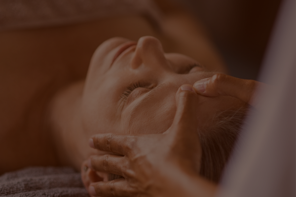 Person receiving a facial massage or therapy with closed eyes.