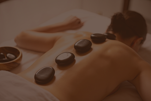Back of a person receiving hot stone massage with four heated stones aligned along their back